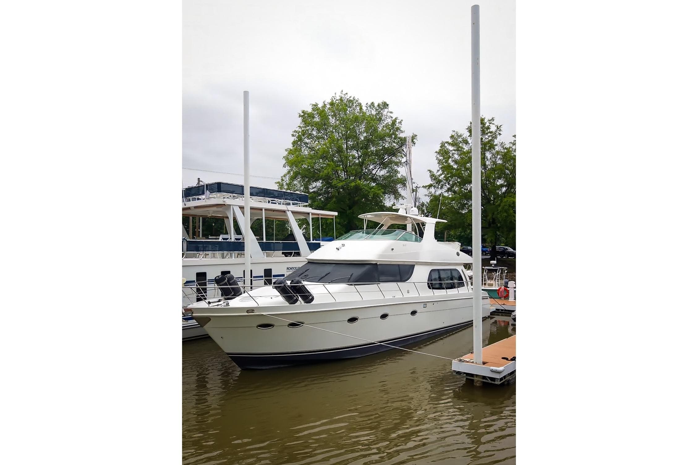 2006 Carver 56 Voyager yacht docked at marina, surrounded by trees and calm water.