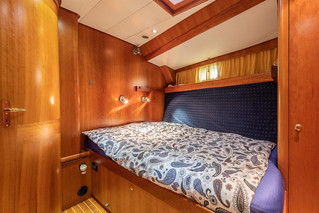 Cozy cabin interior of 2001 Nordia 58 yacht with wooden paneling and patterned bedding.