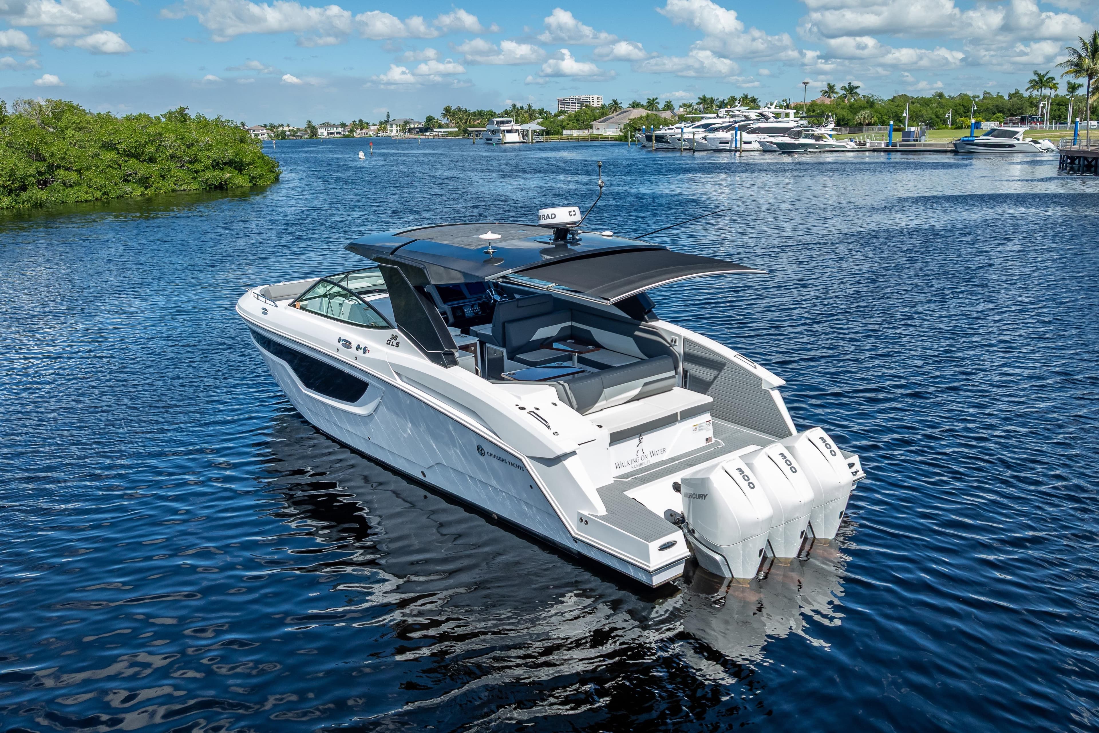 2022 Cruisers Yachts 38 GLS OB on serene water, showcasing sleek design and triple outboard engines.
