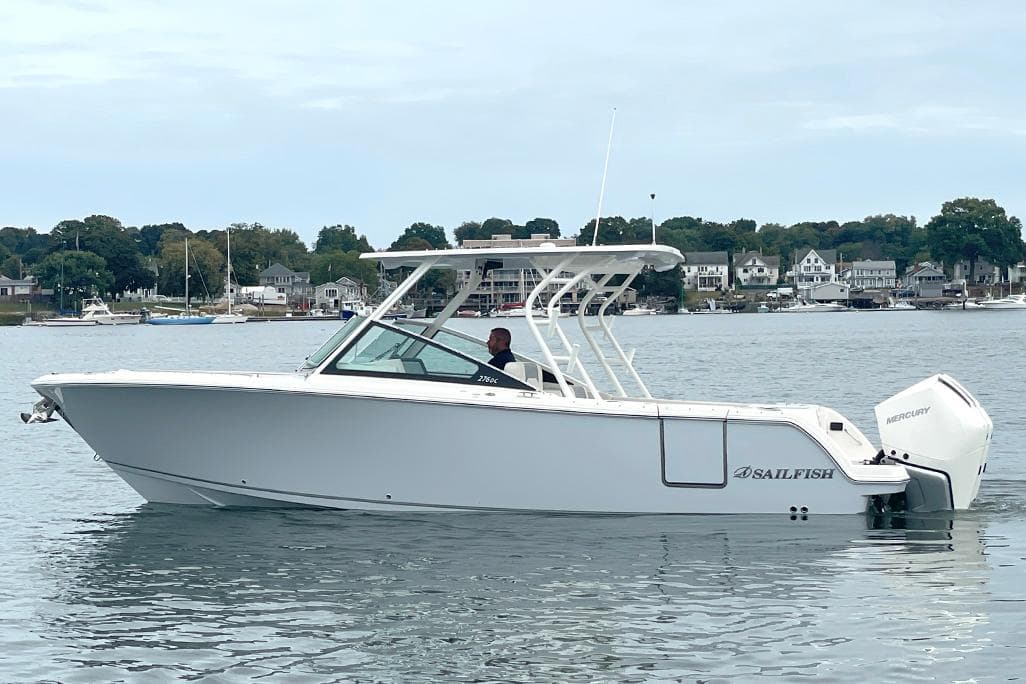 2025 Sailfish 276 DC boat on calm water near a coastal town.