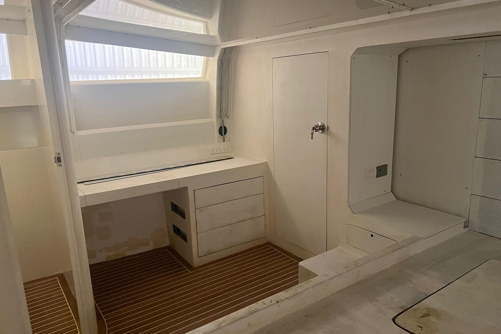 Interior of 2025 Custom 65 Power Cat with modern white cabinetry and wood flooring.