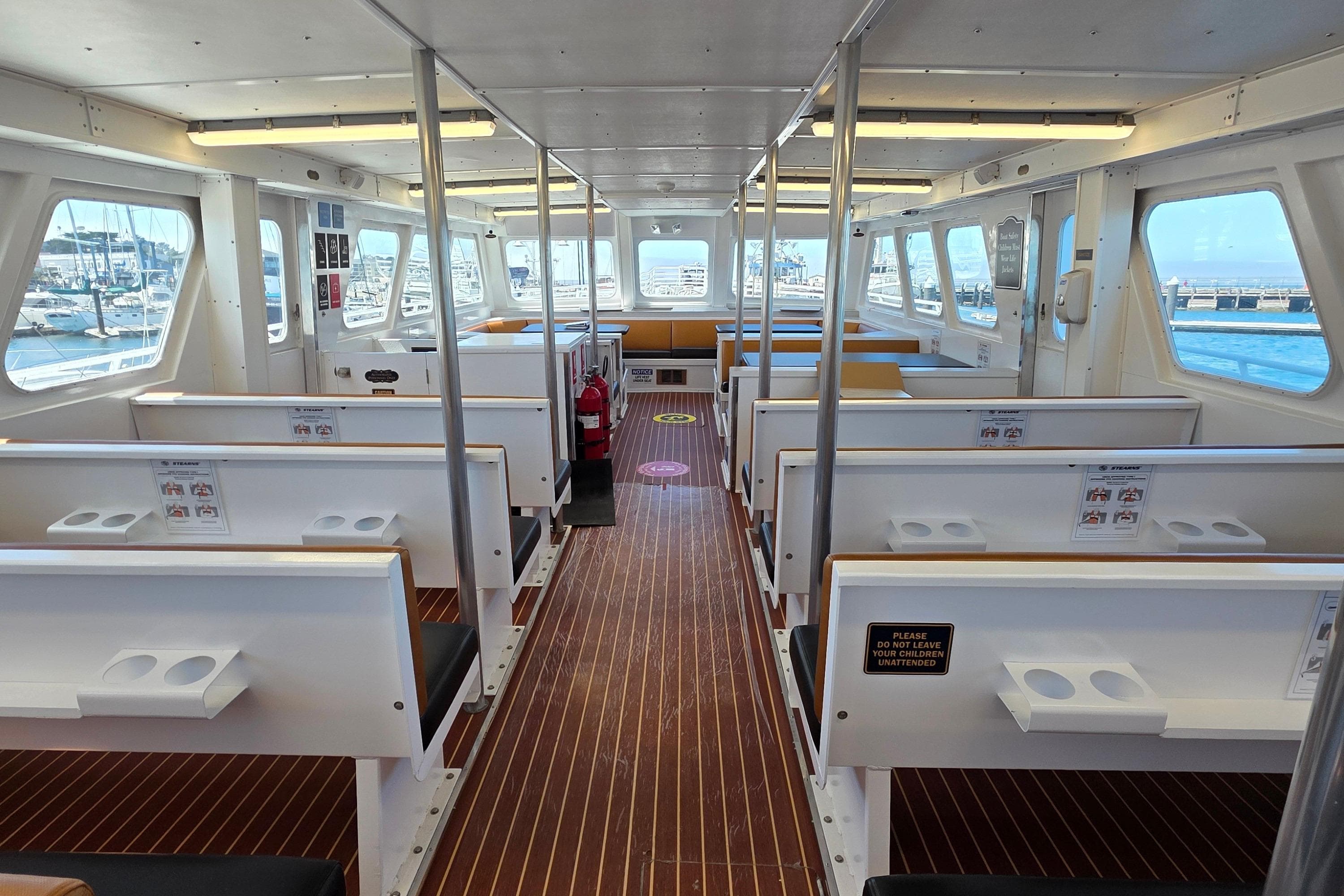 Interior of 1986 Gulf Craft Passenger boat with seating and windows overlooking marina.