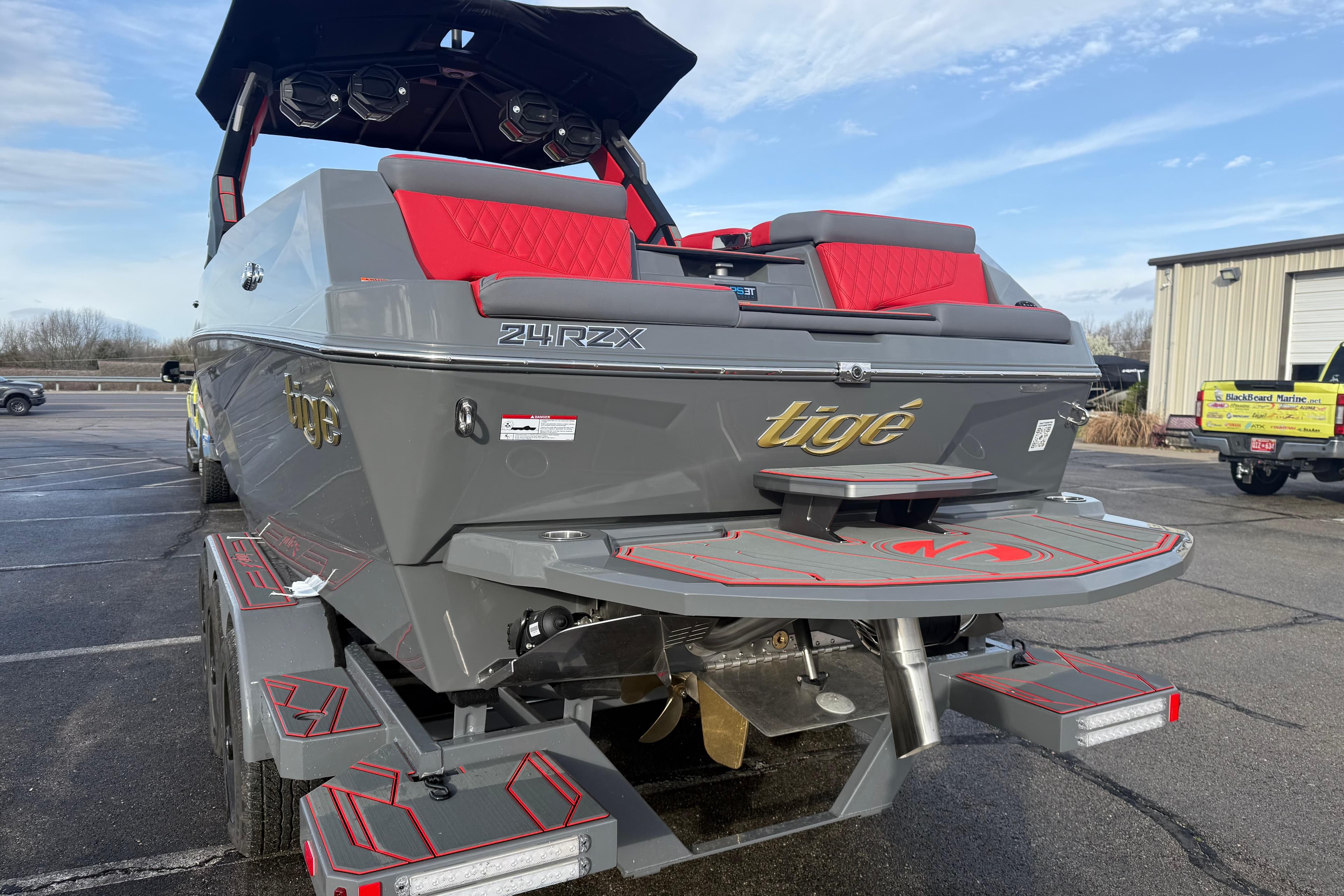 2026 Tigé 24RZX boat with sleek gray design and red accents, parked outdoors.
