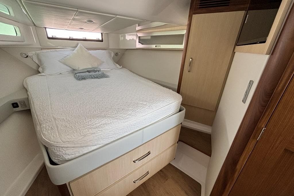 Luxurious cabin interior of 2026 Regal 36 XO yacht with cozy bed and storage.
