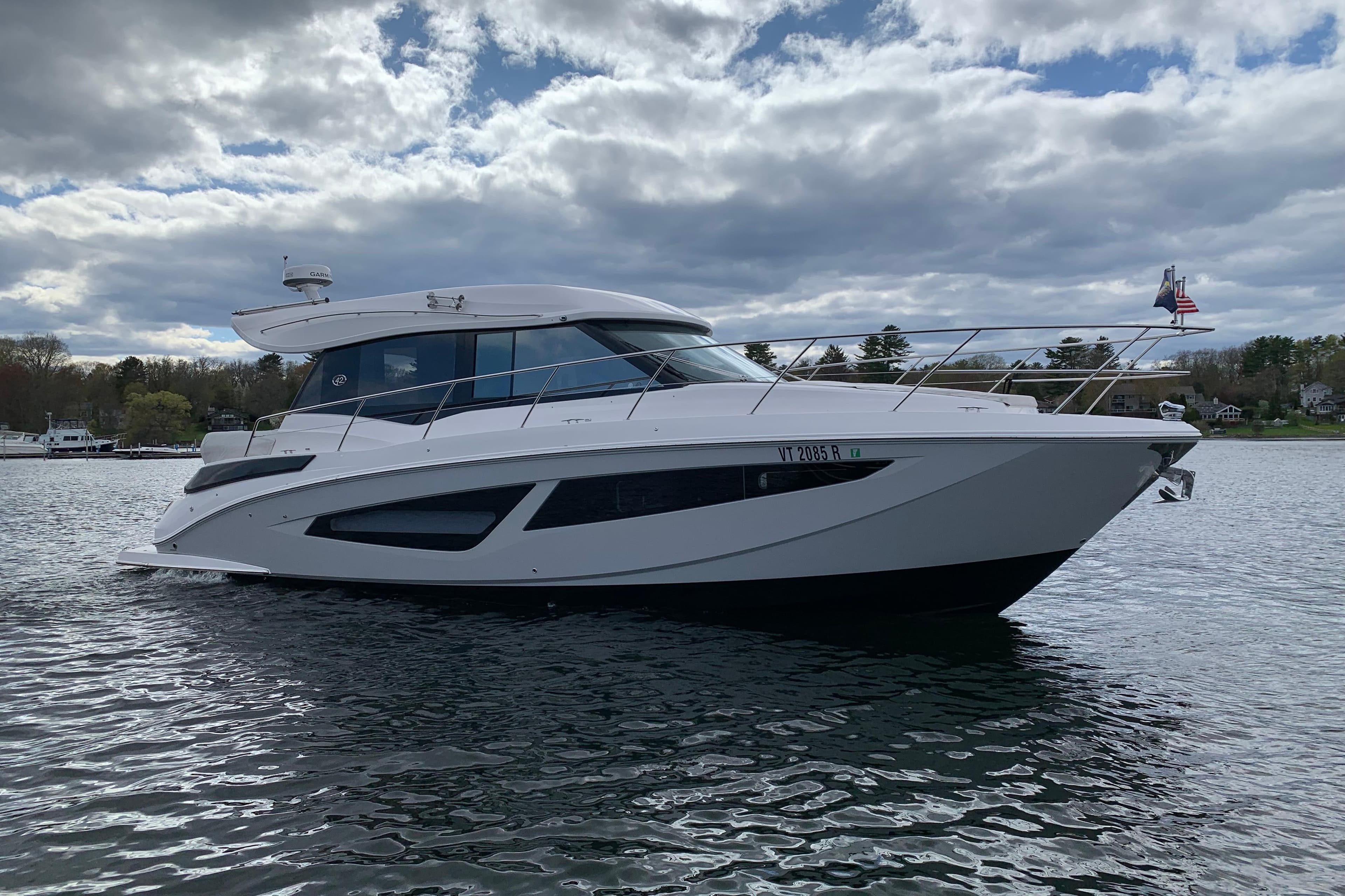 2019 Regal 42 Grande Coupe yacht on a calm lake under cloudy skies.