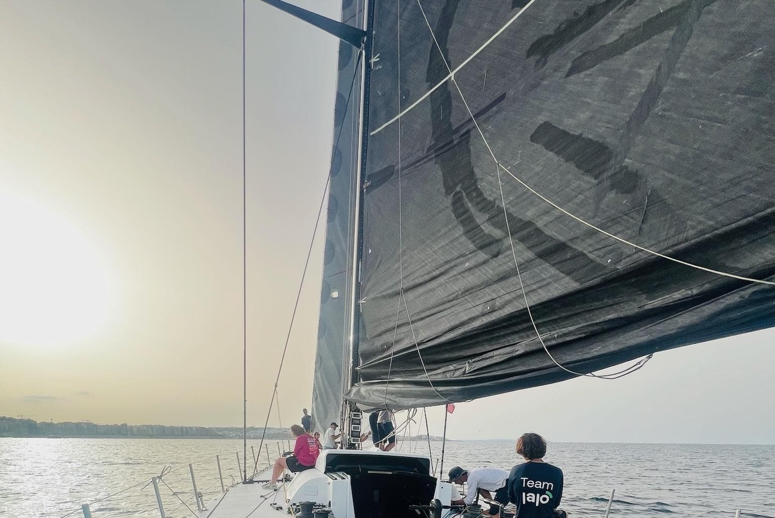 Sailing on a 2005 Green Marine Volvo Ocean 70 at sunset, crew onboard.