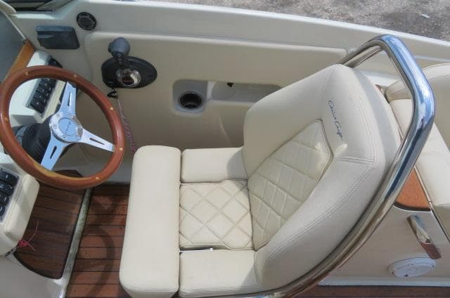 2021 Chris-Craft Launch 27 cockpit with beige leather seat and wooden steering wheel.