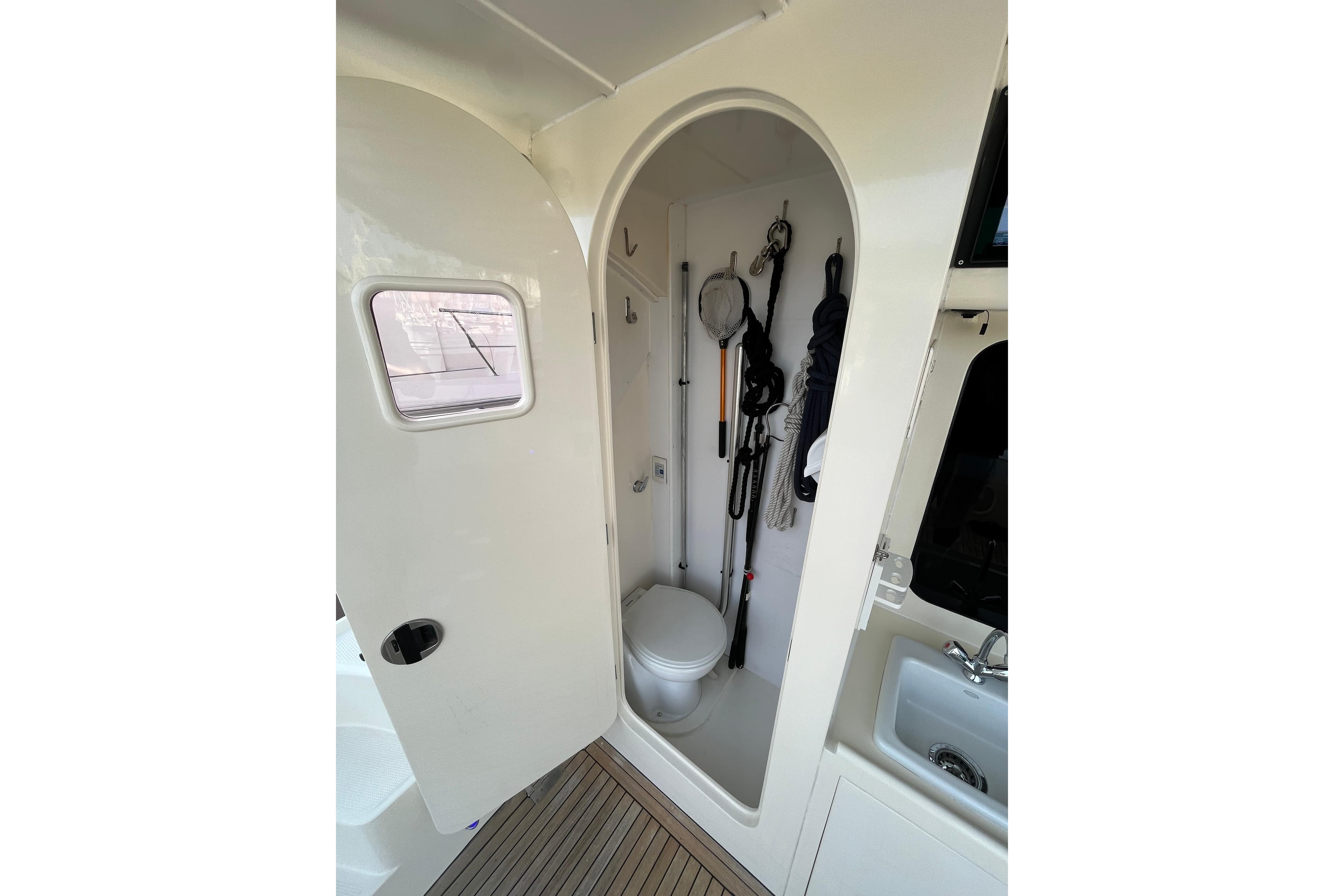 2007 Mikelson Sportfisher boat interior with compact bathroom and fishing gear storage.
