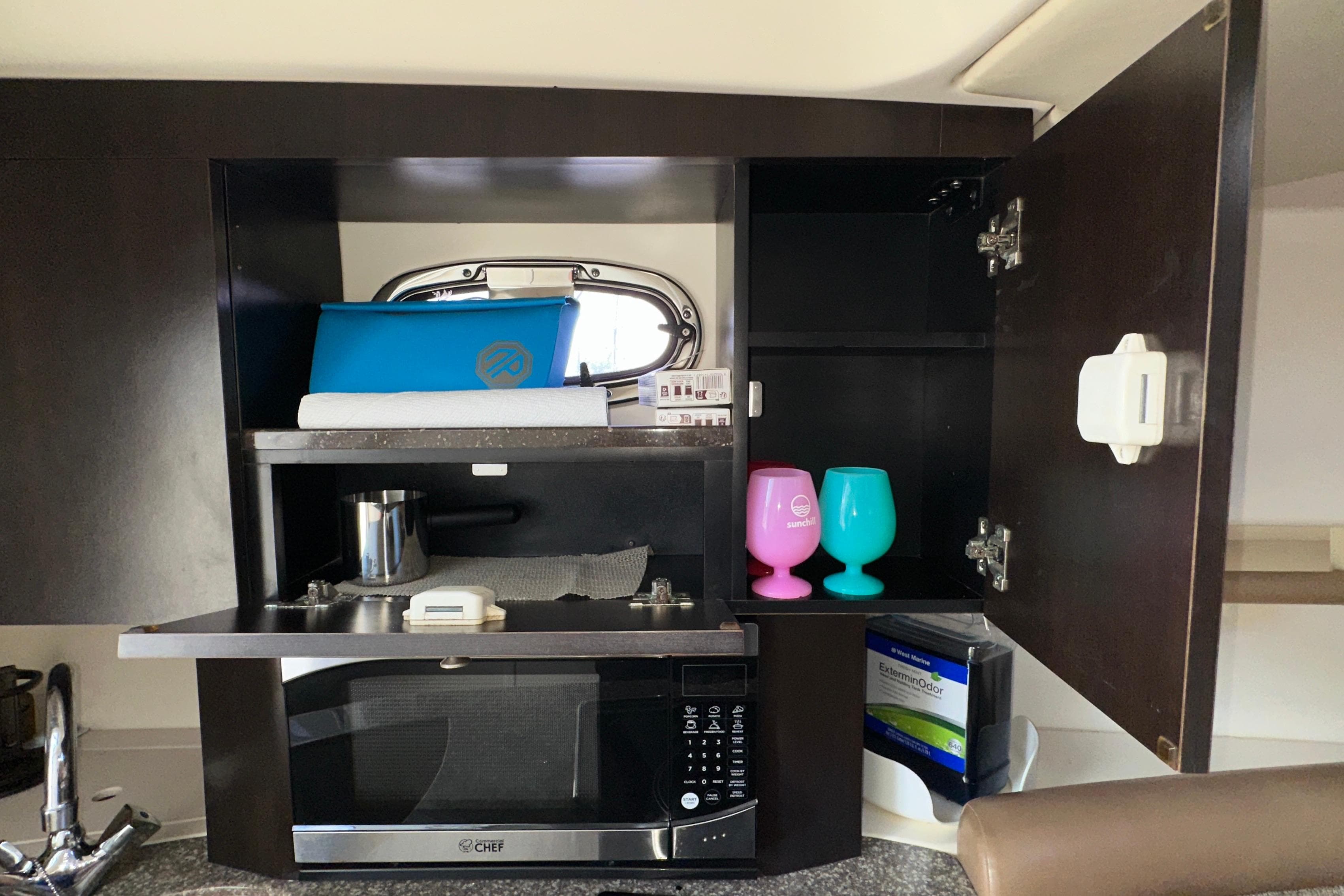 2006 Boston Whaler 285 Conquest interior with microwave, colorful cups, and storage cabinets.