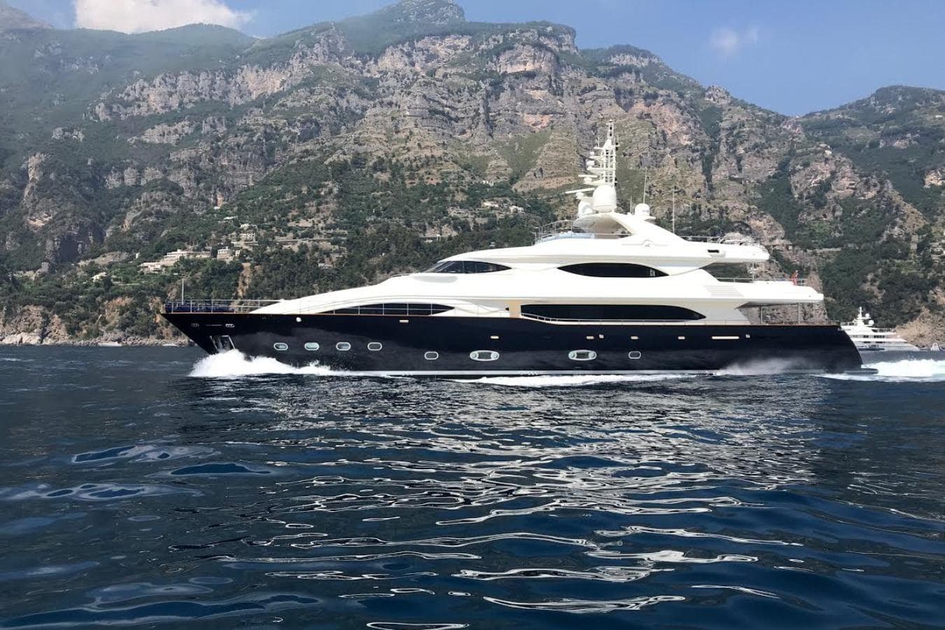 Luxurious 2007 CRN 128 yacht cruising near scenic mountainous coastline.