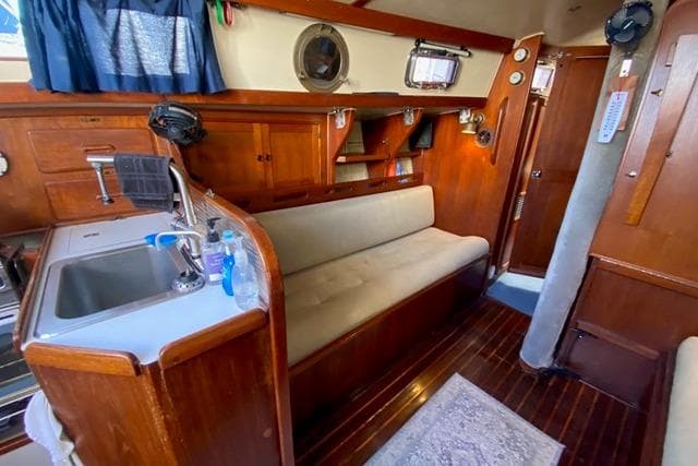1979 Morgan 321 yacht interior with wooden cabinetry, sink, and cushioned seating.