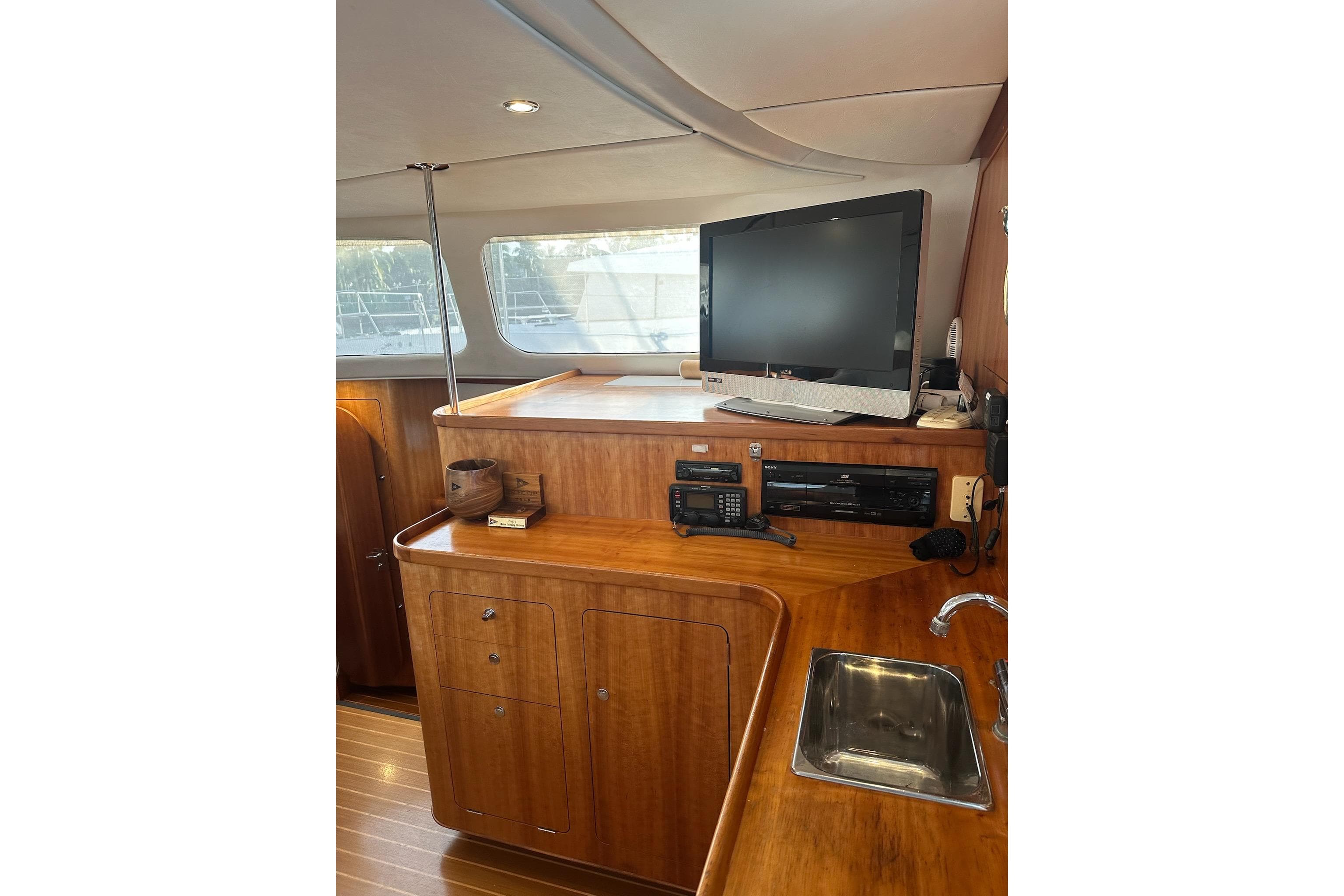 Interior of 2002 PDQ Antares yacht with wooden cabinetry, TV, and sink.