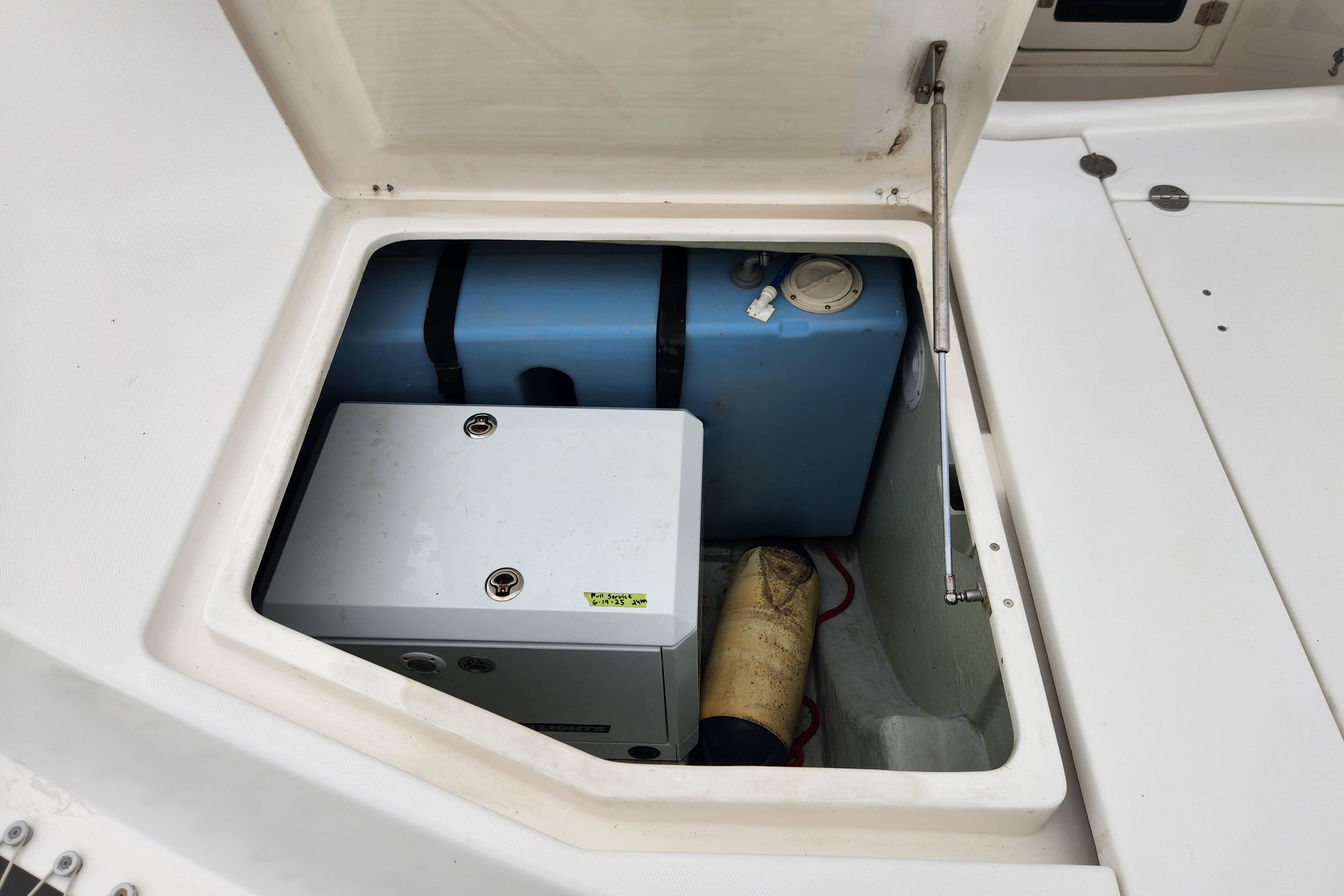 Open storage compartment on 2015 Leopard 44 boat, showing equipment and blue tank.