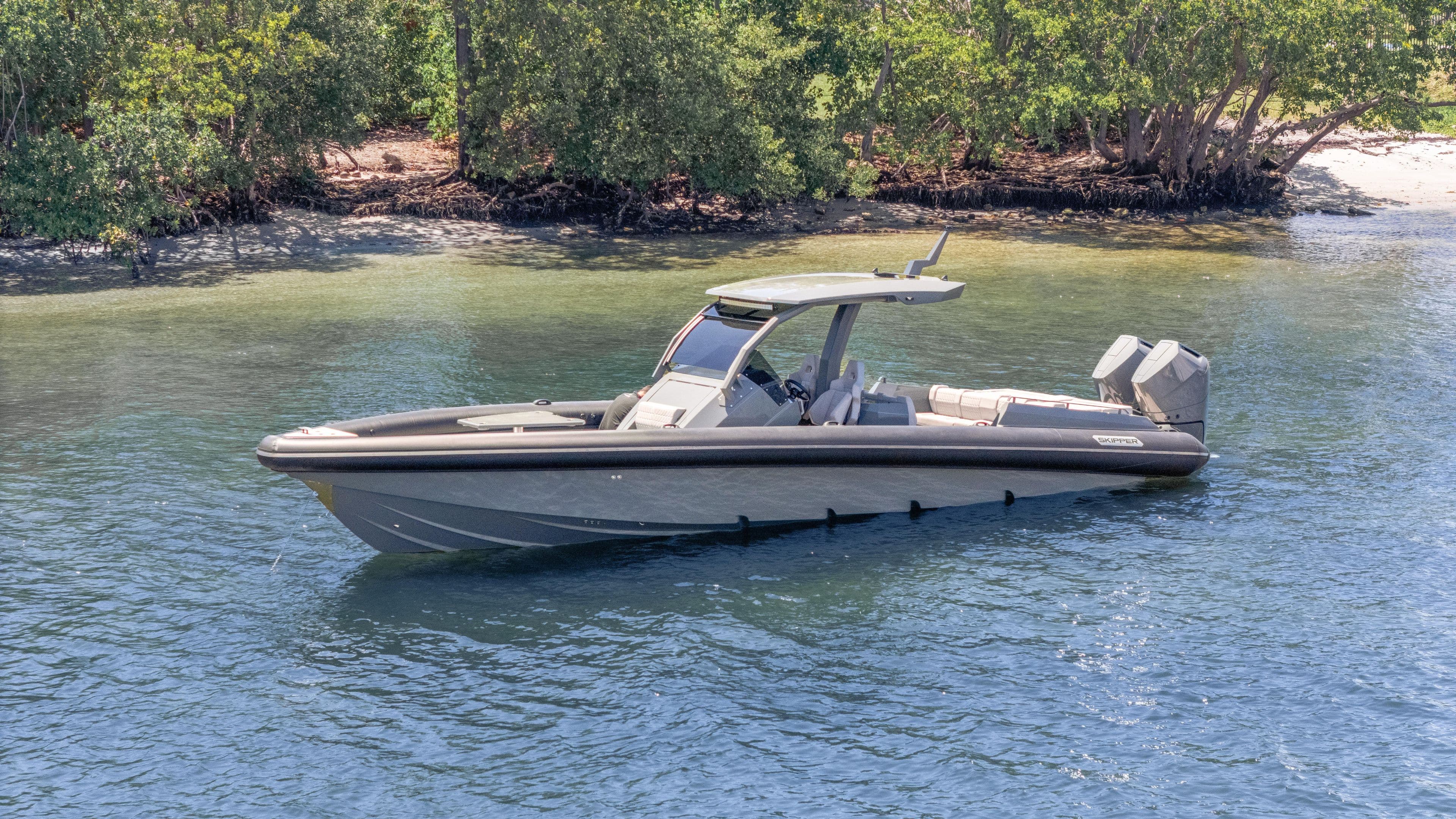 2025 Skipper-BSK 38 boat on calm water near a lush shoreline.
