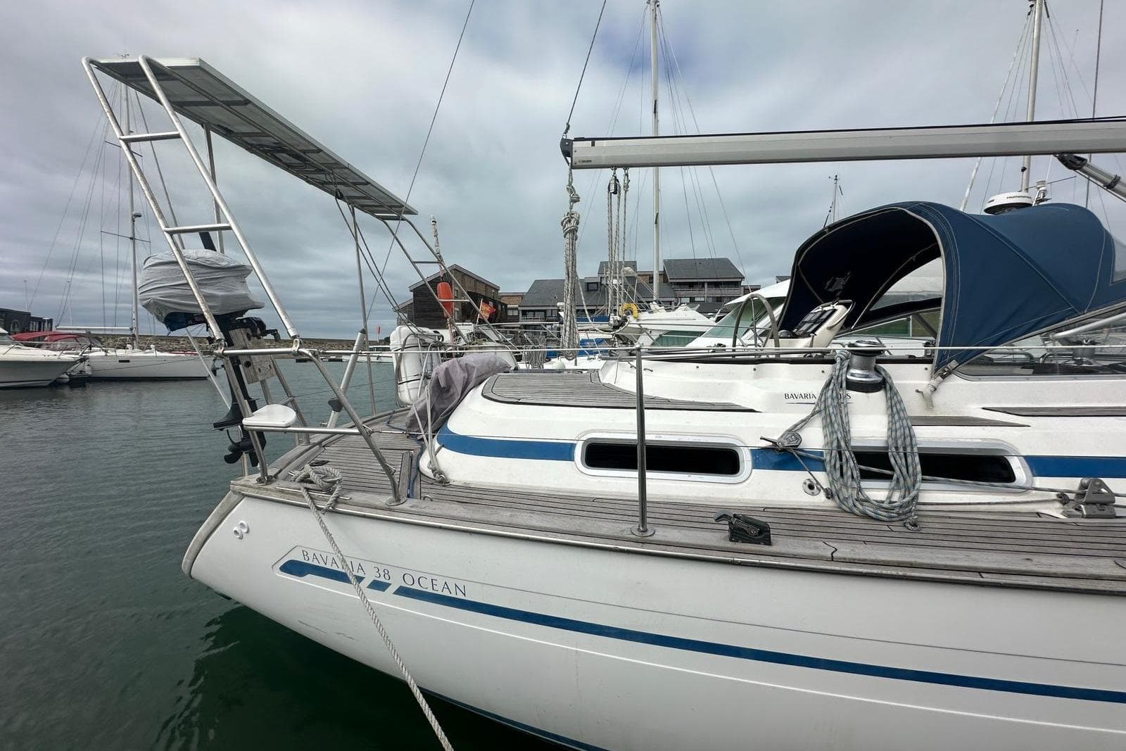 1999 Bavaria Yachts 38 Ocean sailboat docked in marina, featuring blue accents and solar panel.