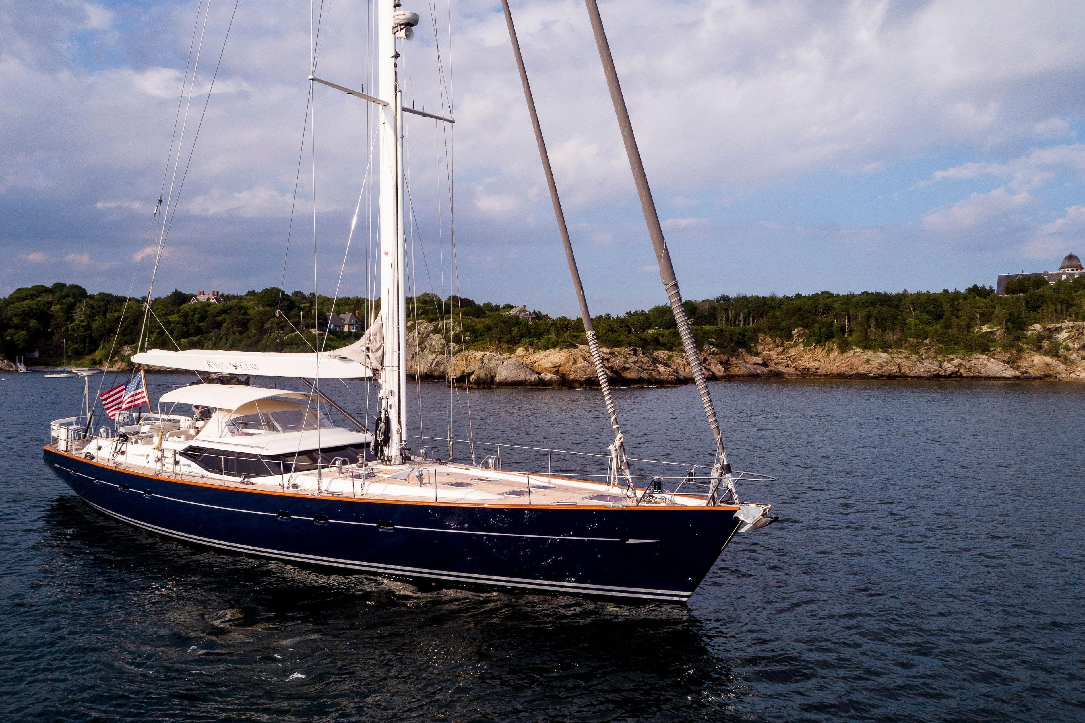 Luxurious 2007 Oyster 82 yacht sailing near scenic coastline under a partly cloudy sky.