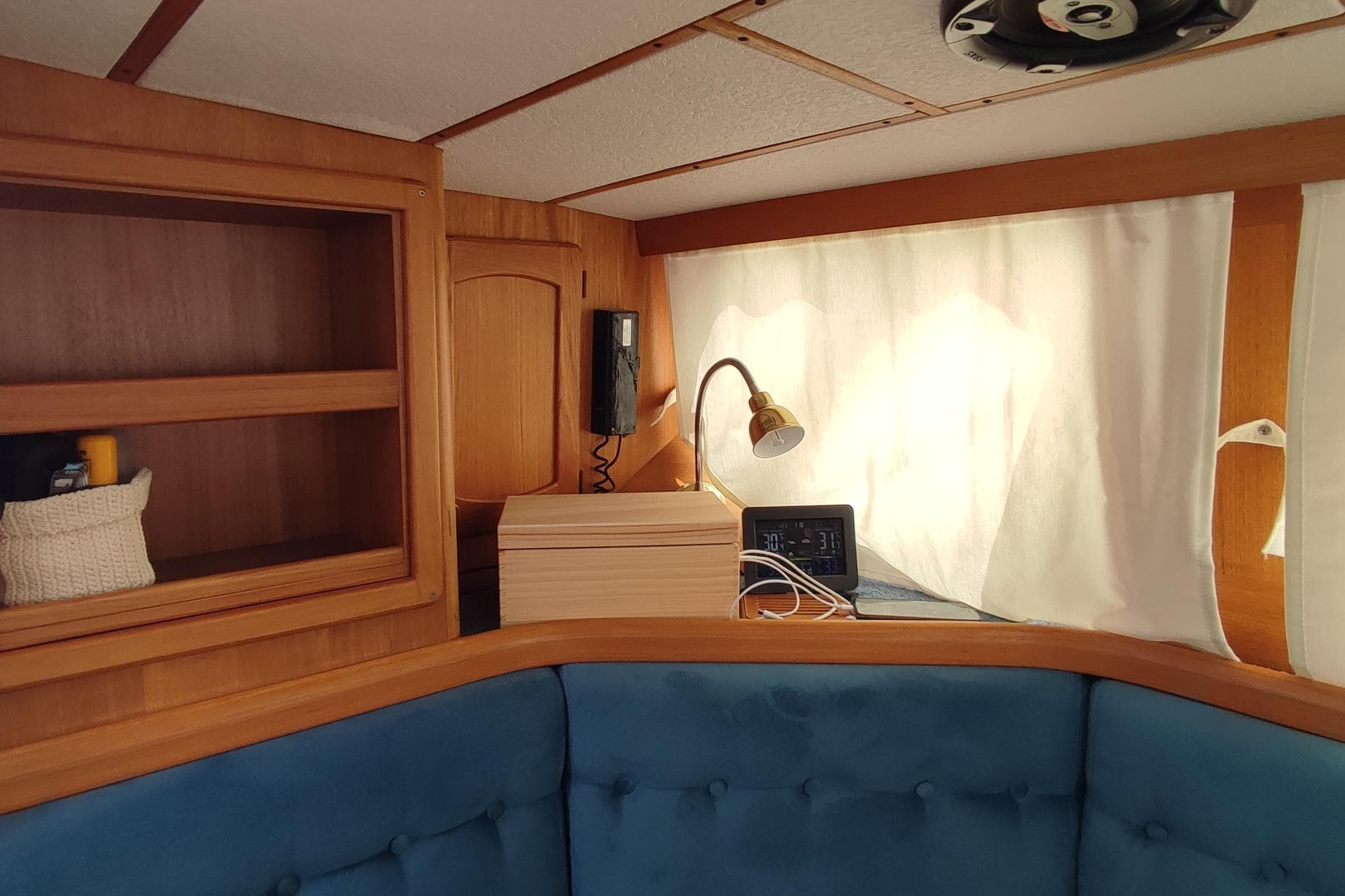 Cozy interior of 1997 Nauticat 42 sailboat with wooden shelves and blue seating.