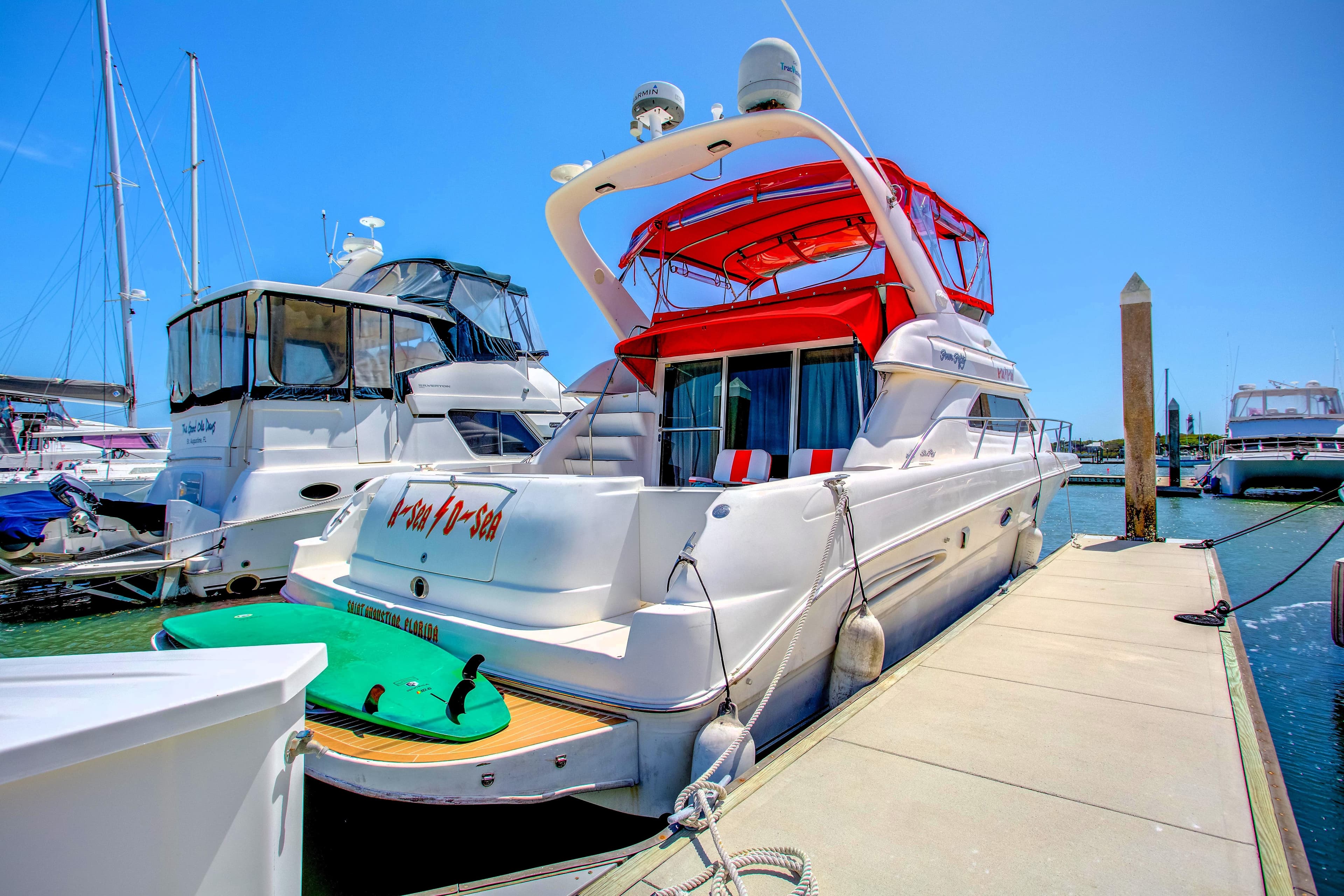 2000 Sea Ray 450 Express Bridge yacht docked at marina with vibrant red canopy.