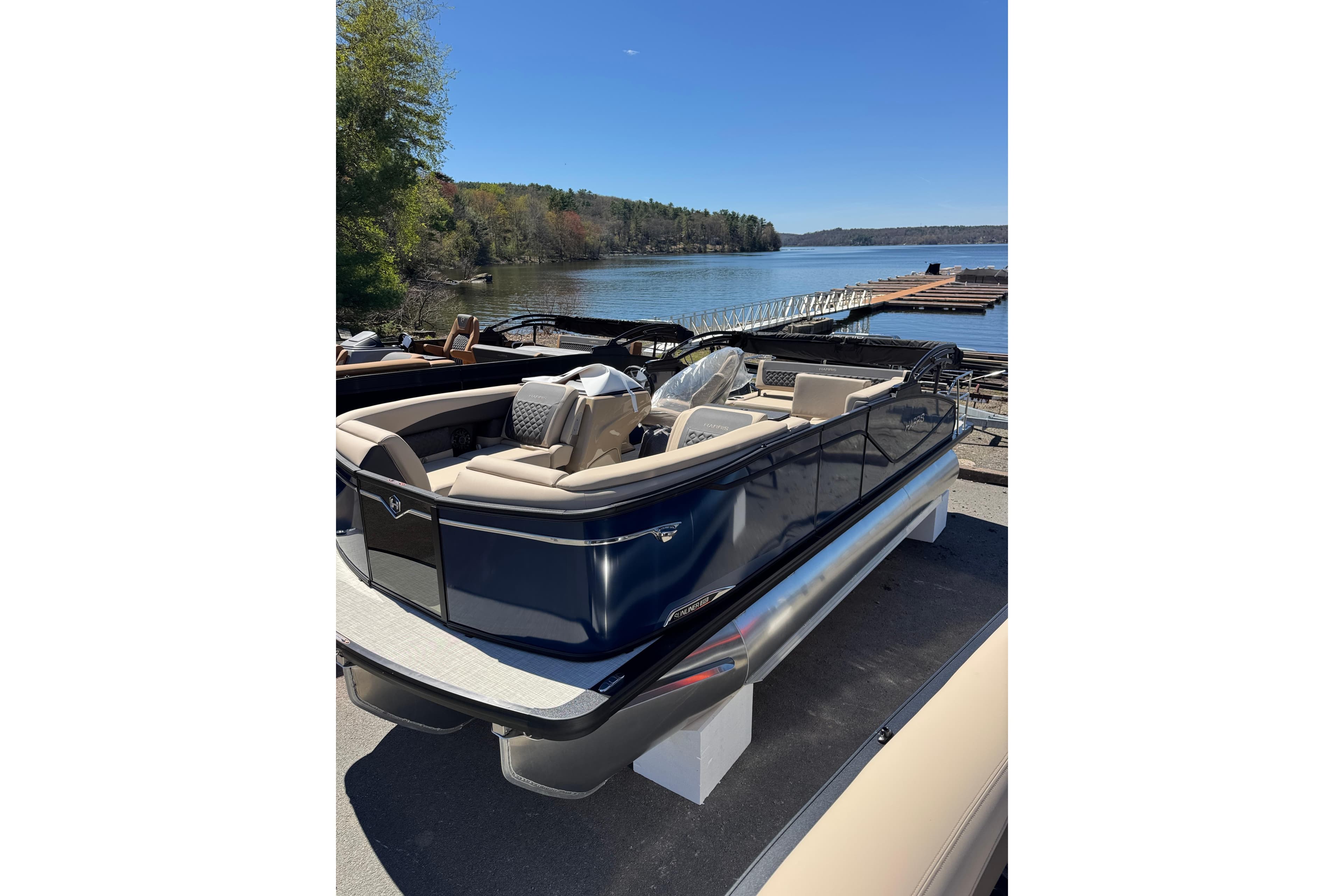 2026 Harris Sunliner 210 pontoon boat docked by a serene lake.
