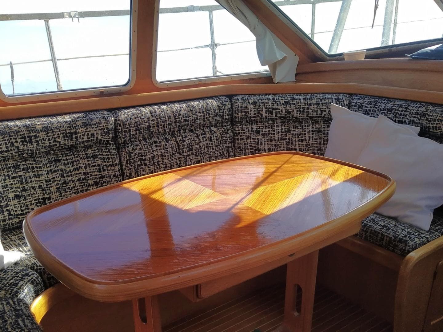 Cozy interior of 1996 Nauticat 42 sailboat with wooden table and cushioned seating.
