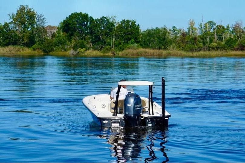 2023 Scout 177 Sport boat cruising on a serene lake with lush green shoreline.