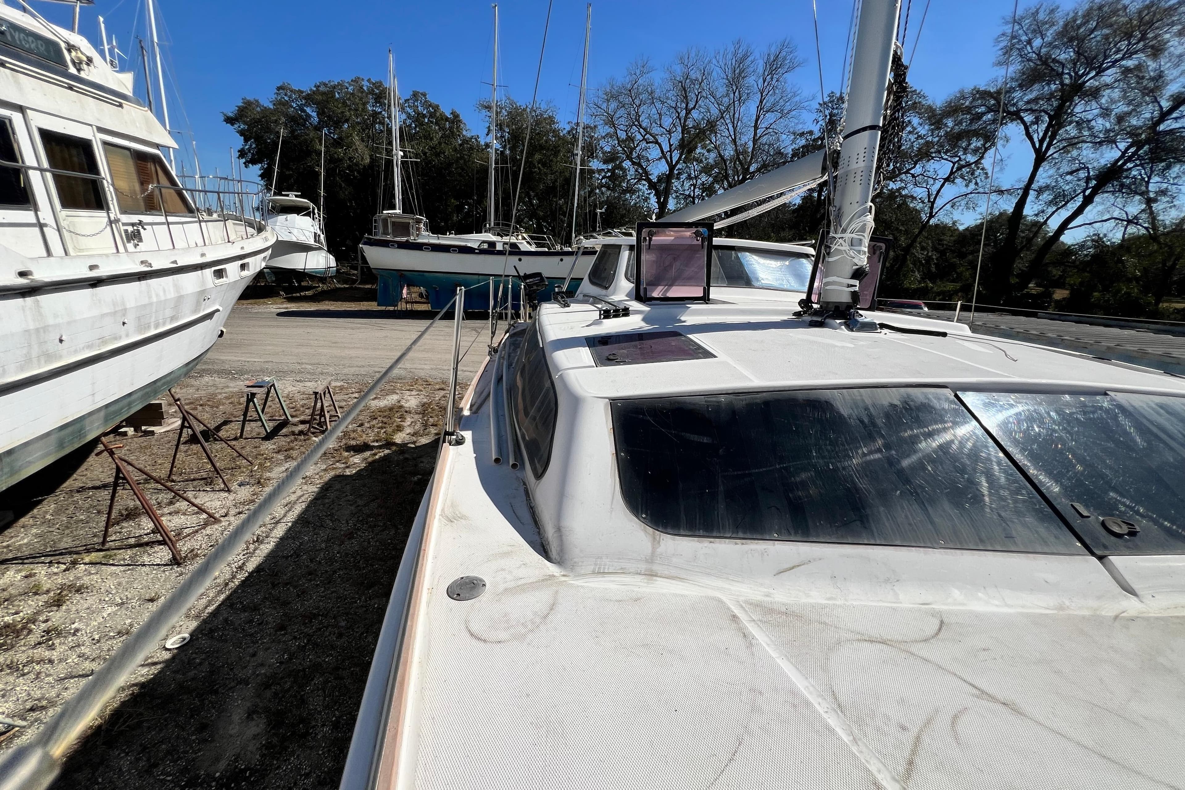 2013 Gemini Legacy 35 sailboat on land, surrounded by other boats and trees.