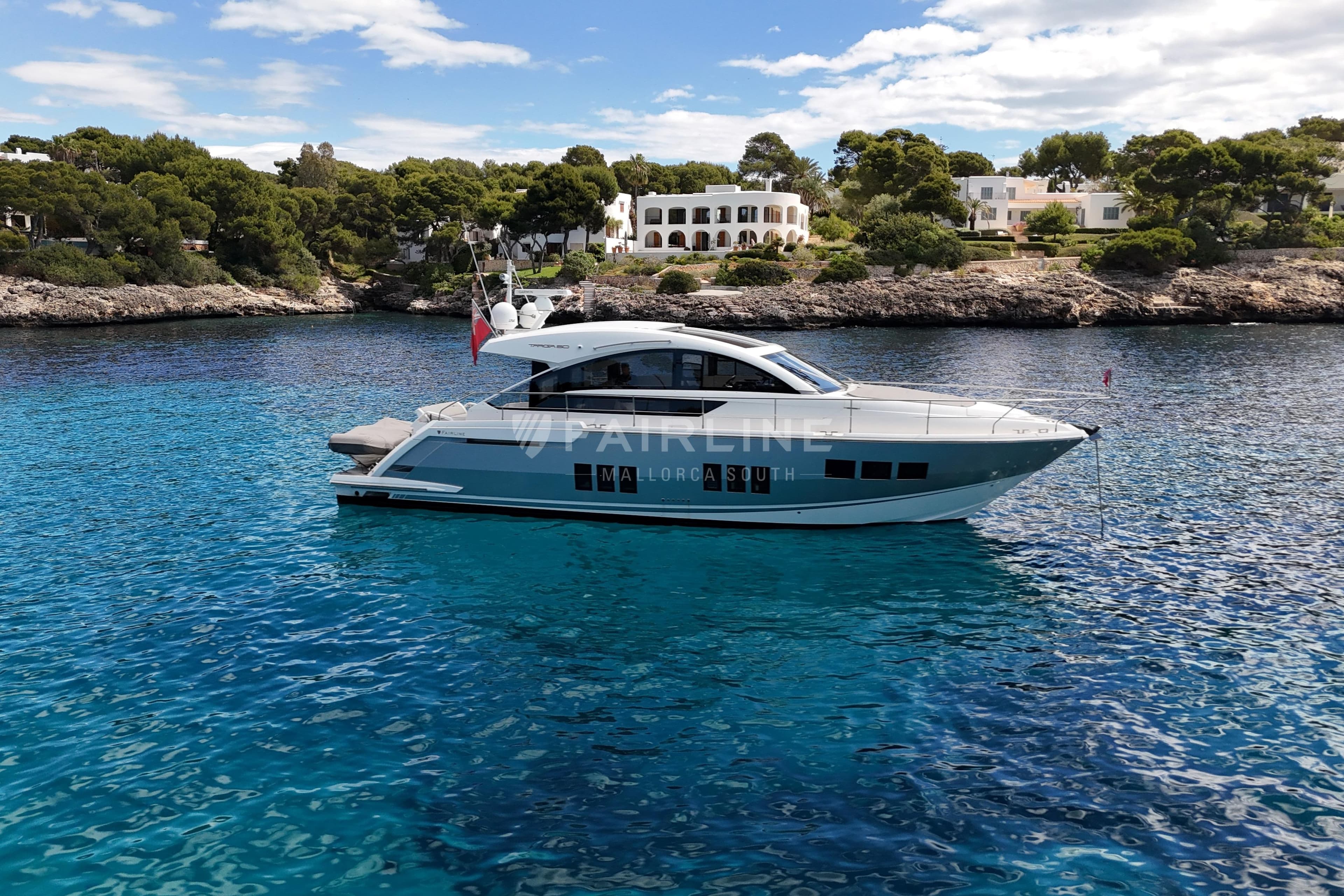 Luxury Fairline Targa 50 GT yacht on clear blue water, coastal backdrop, 2012 model.