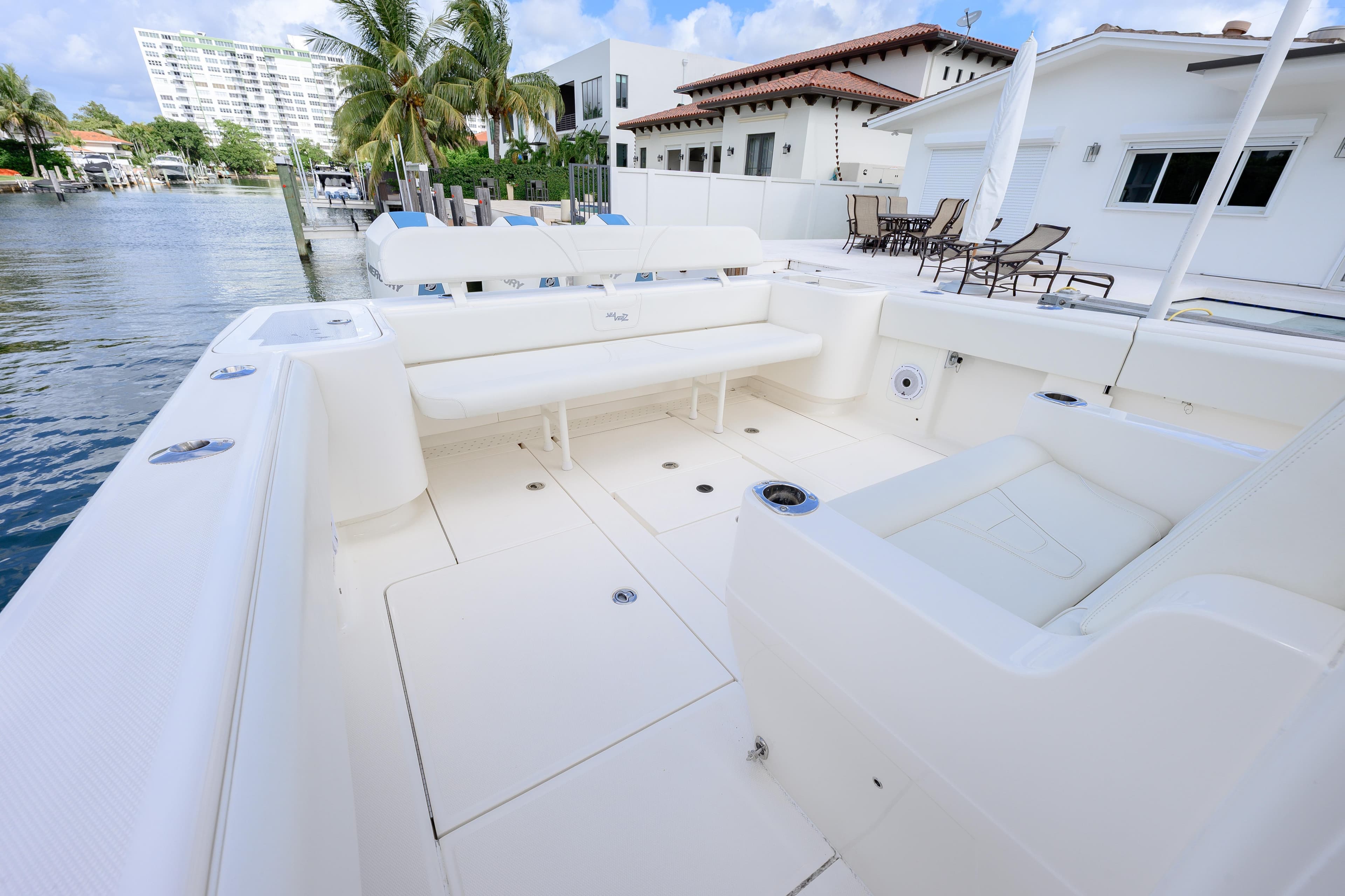 2023 SeaVee 370z boat with spacious white deck and seating, docked by waterfront homes.