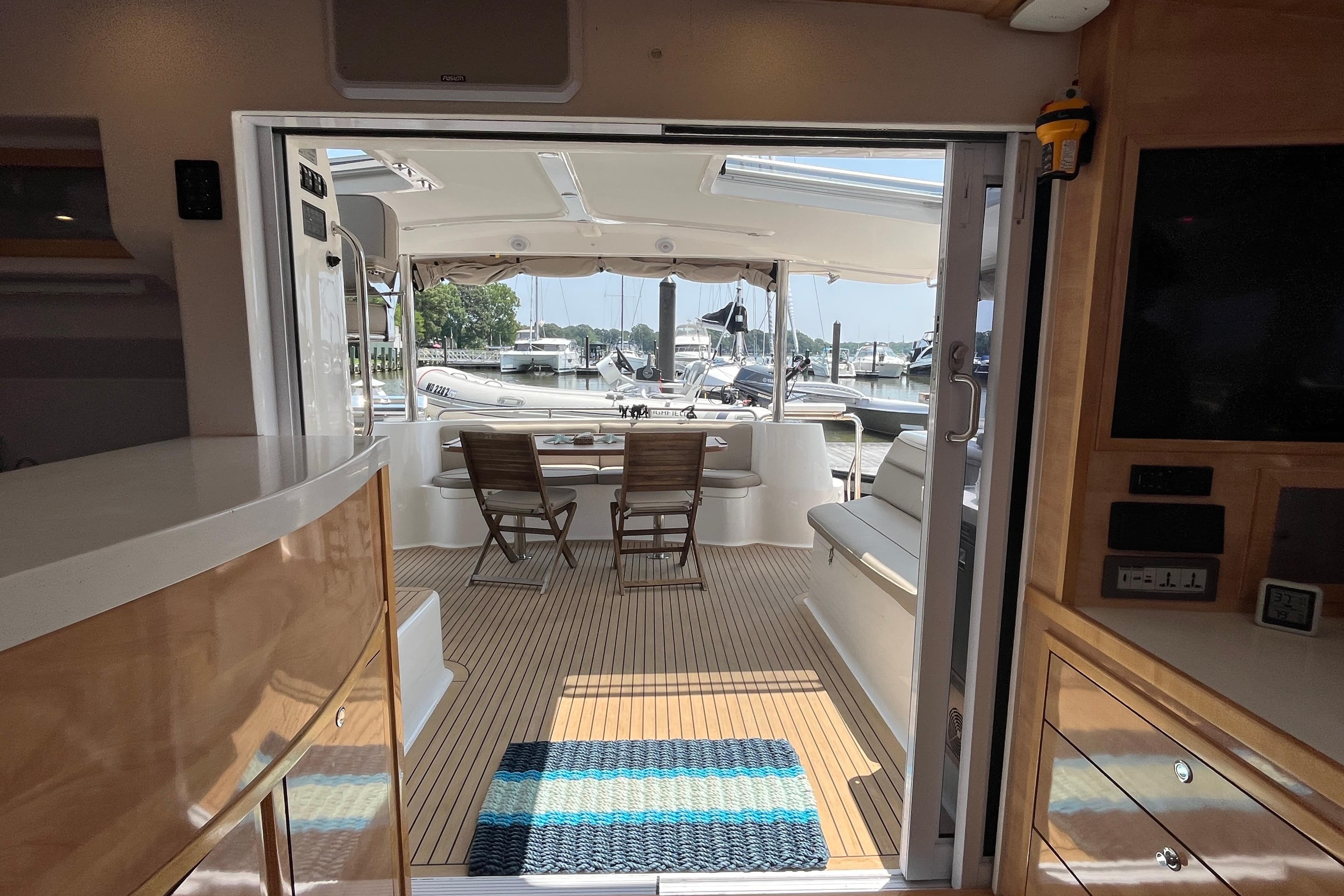 Interior view of 2021 Knysna 500SE yacht, featuring elegant wood finishes and marina backdrop.