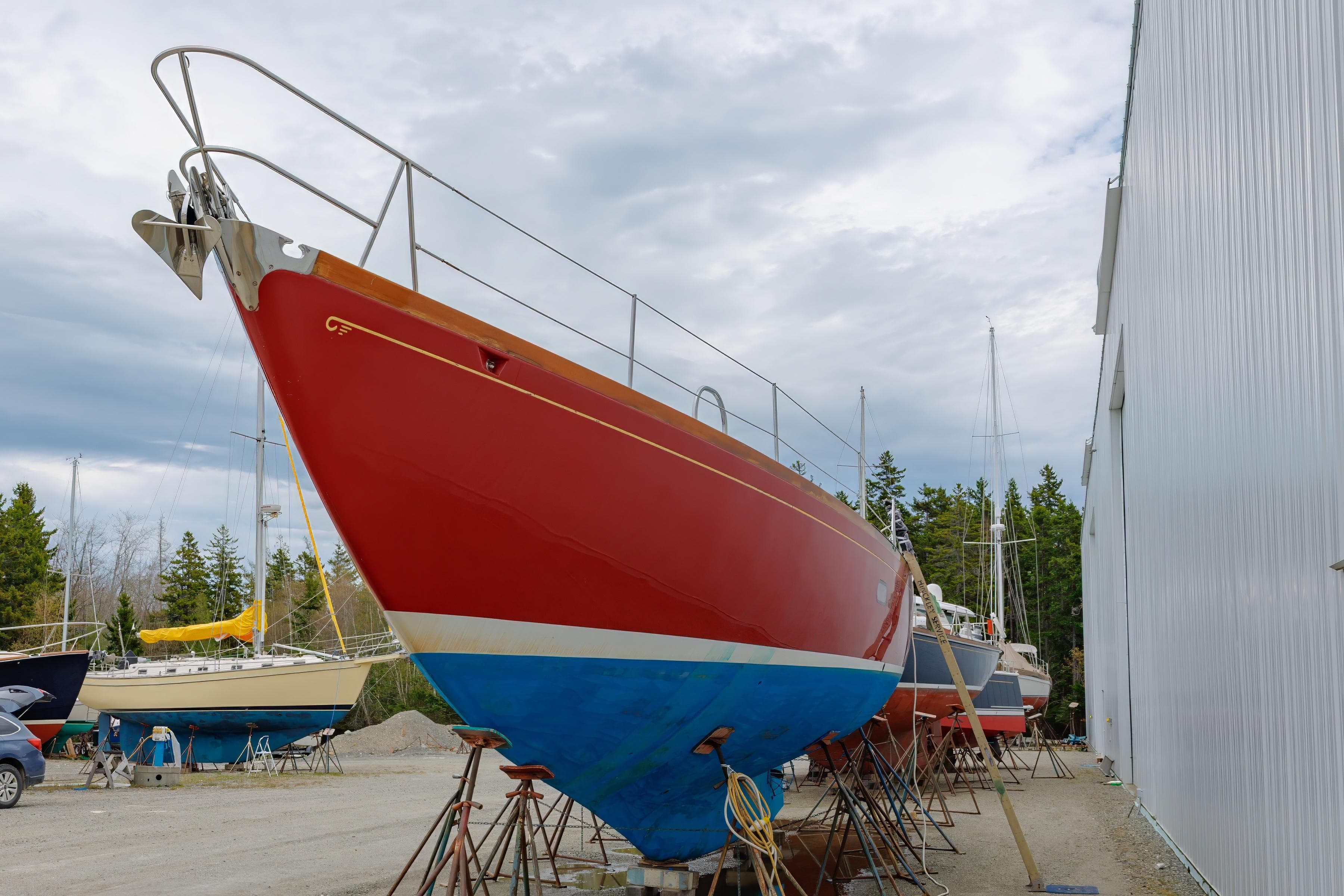 Red 1972 Hinckley 48 sailboat on dry dock near a white building.