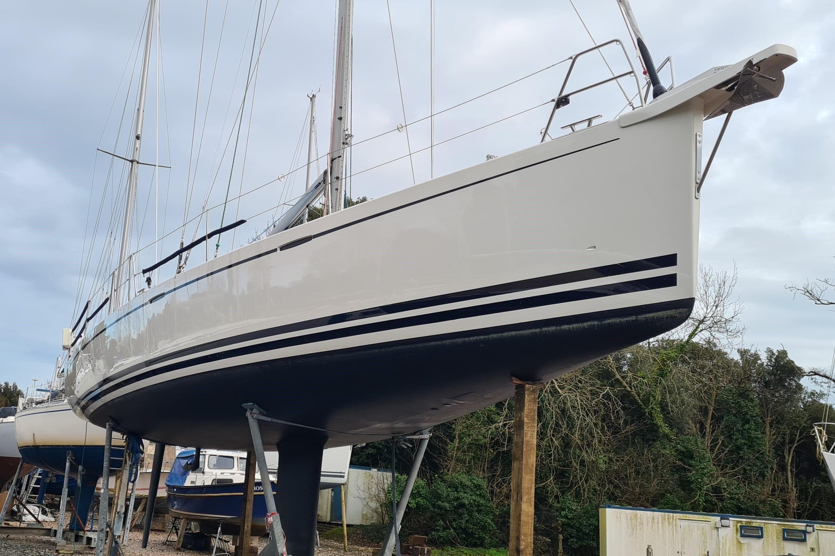 2018 Arcona 435 sailboat on dry dock, side view with trees in background.