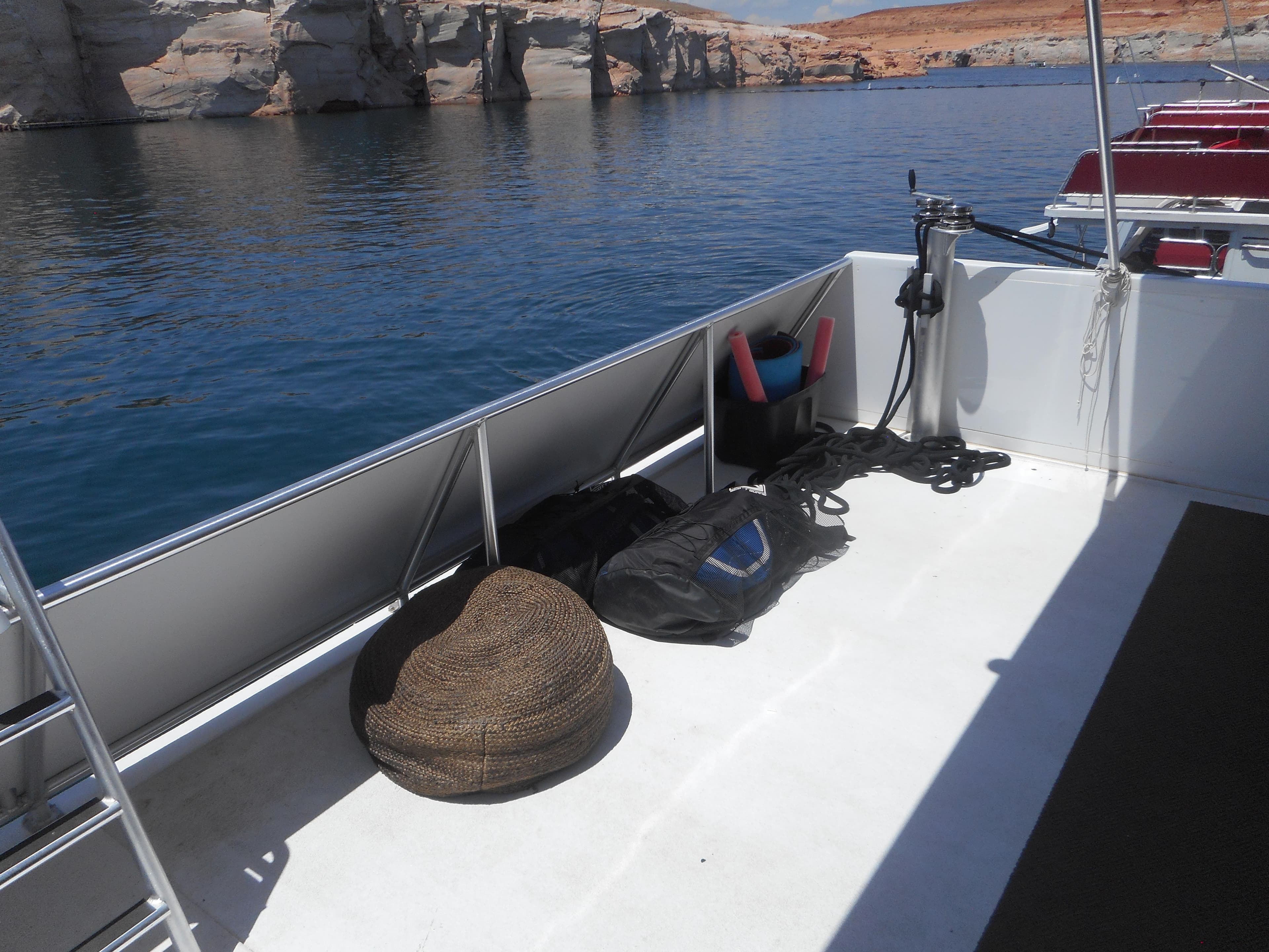 Boat deck with equipment, calm water, and rocky shoreline; Adonia Obsession Trip #12, 2021.