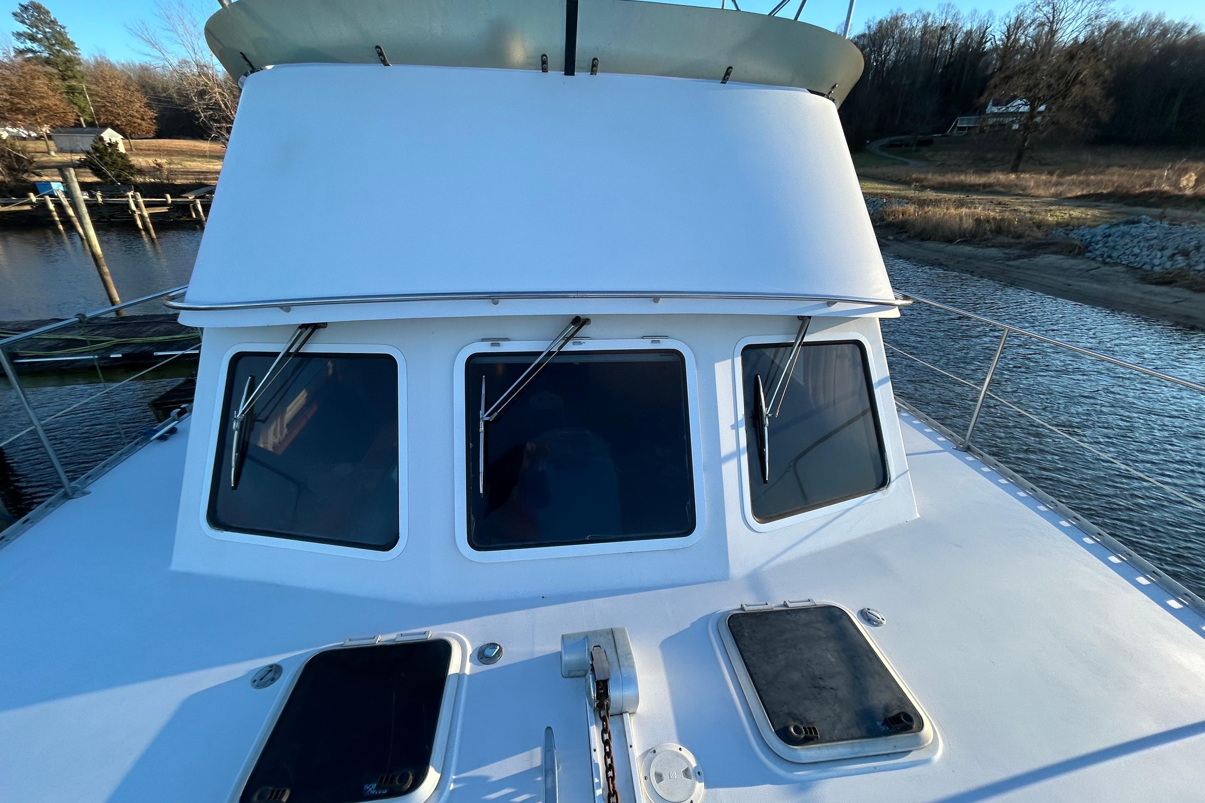 2004 PDQ 34 Power Catamaran on calm water, showcasing front windows and deck hatches.
