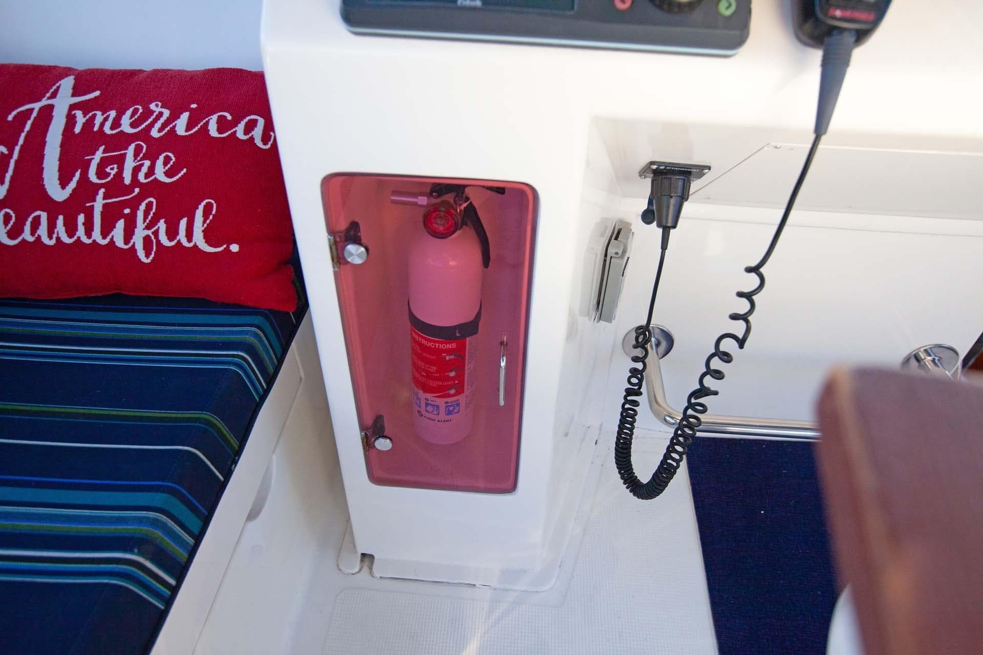 Fire extinguisher in 1997 McKinna 48' Pilot House, with radio and patriotic cushion nearby.