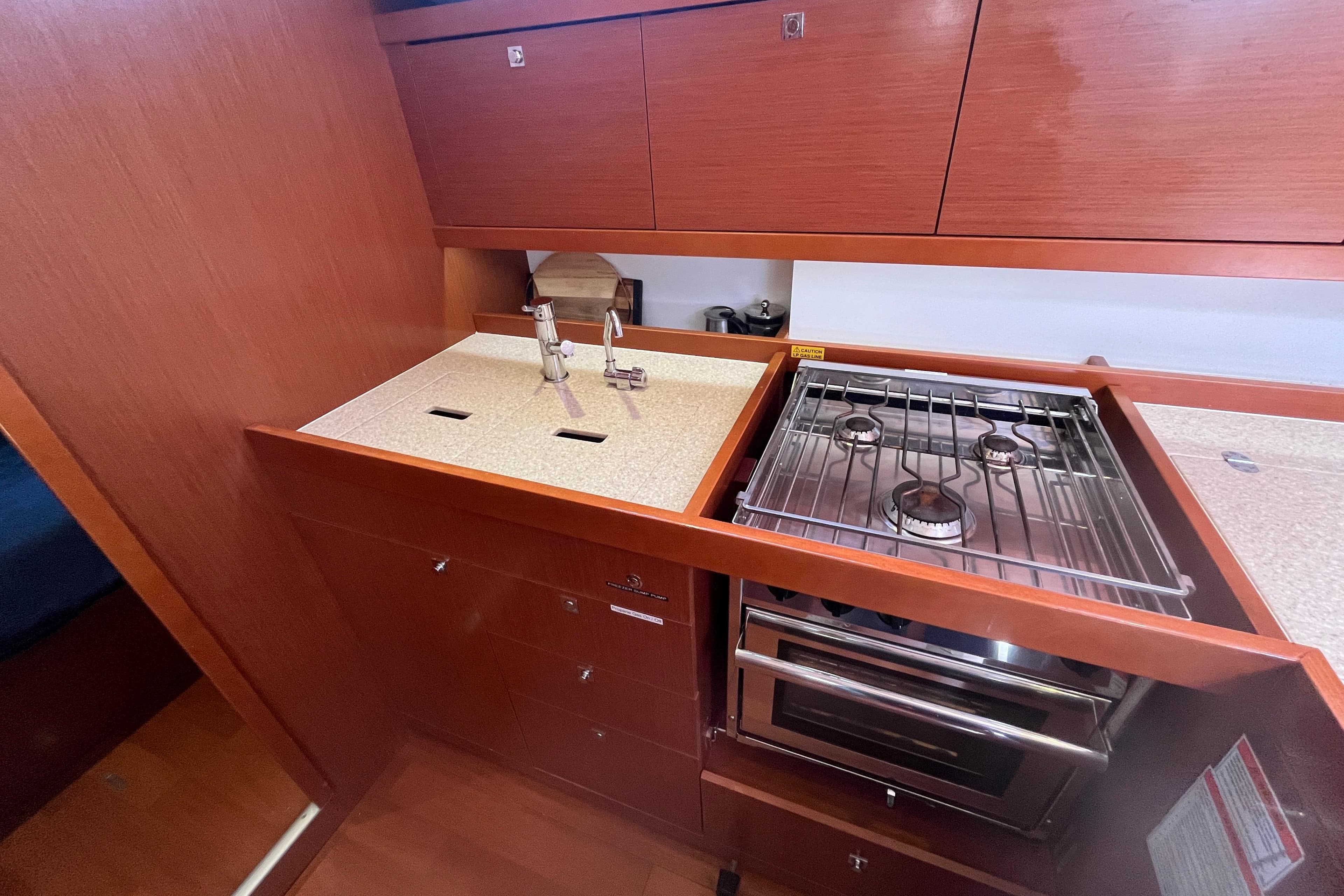 Modern galley kitchen in 2014 Beneteau Oceanis 45 yacht with stove and sink.