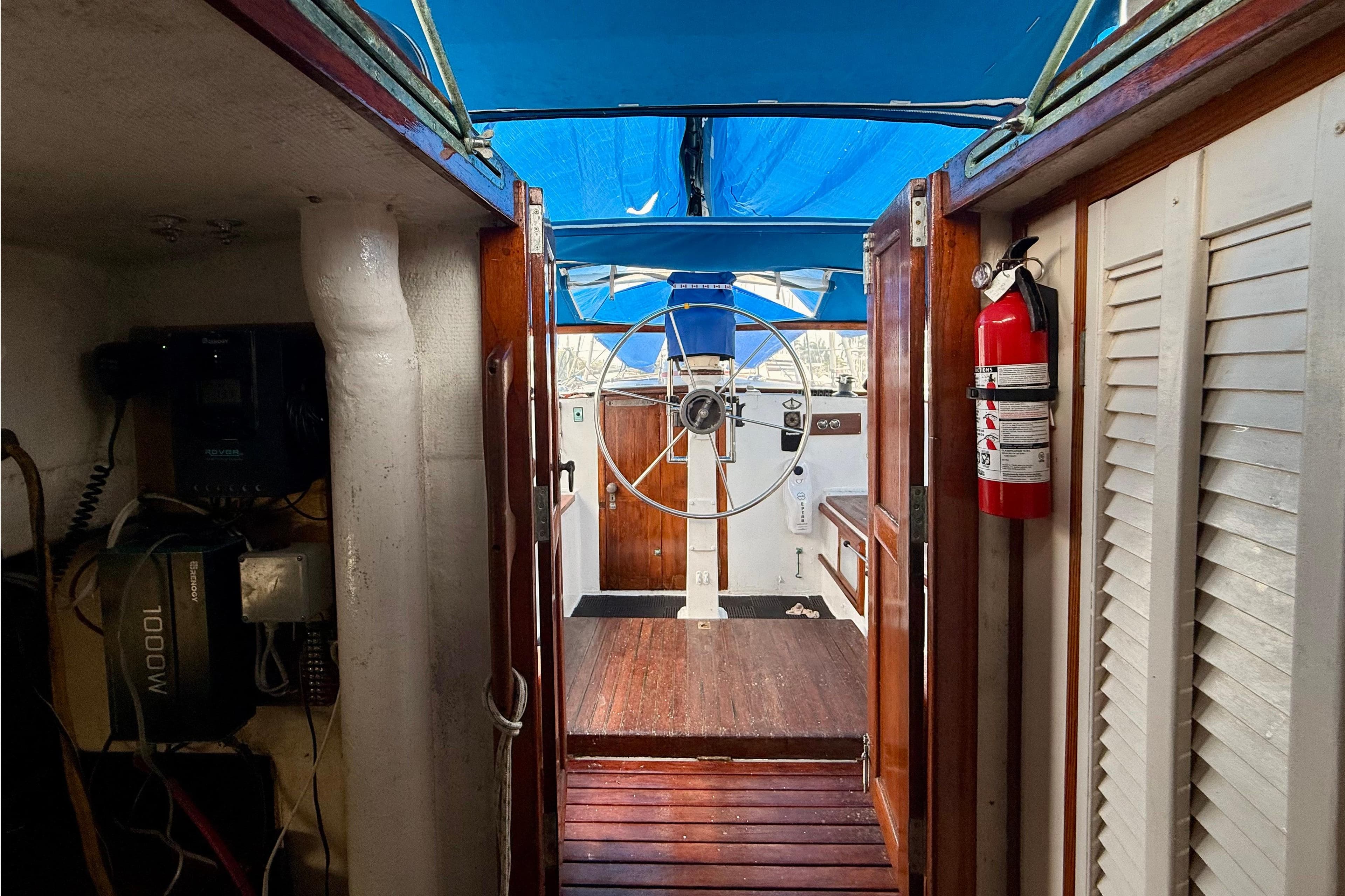 Interior view of 1966 Cheoy Lee Gulf 40 sailboat cockpit with steering wheel and fire extinguisher.