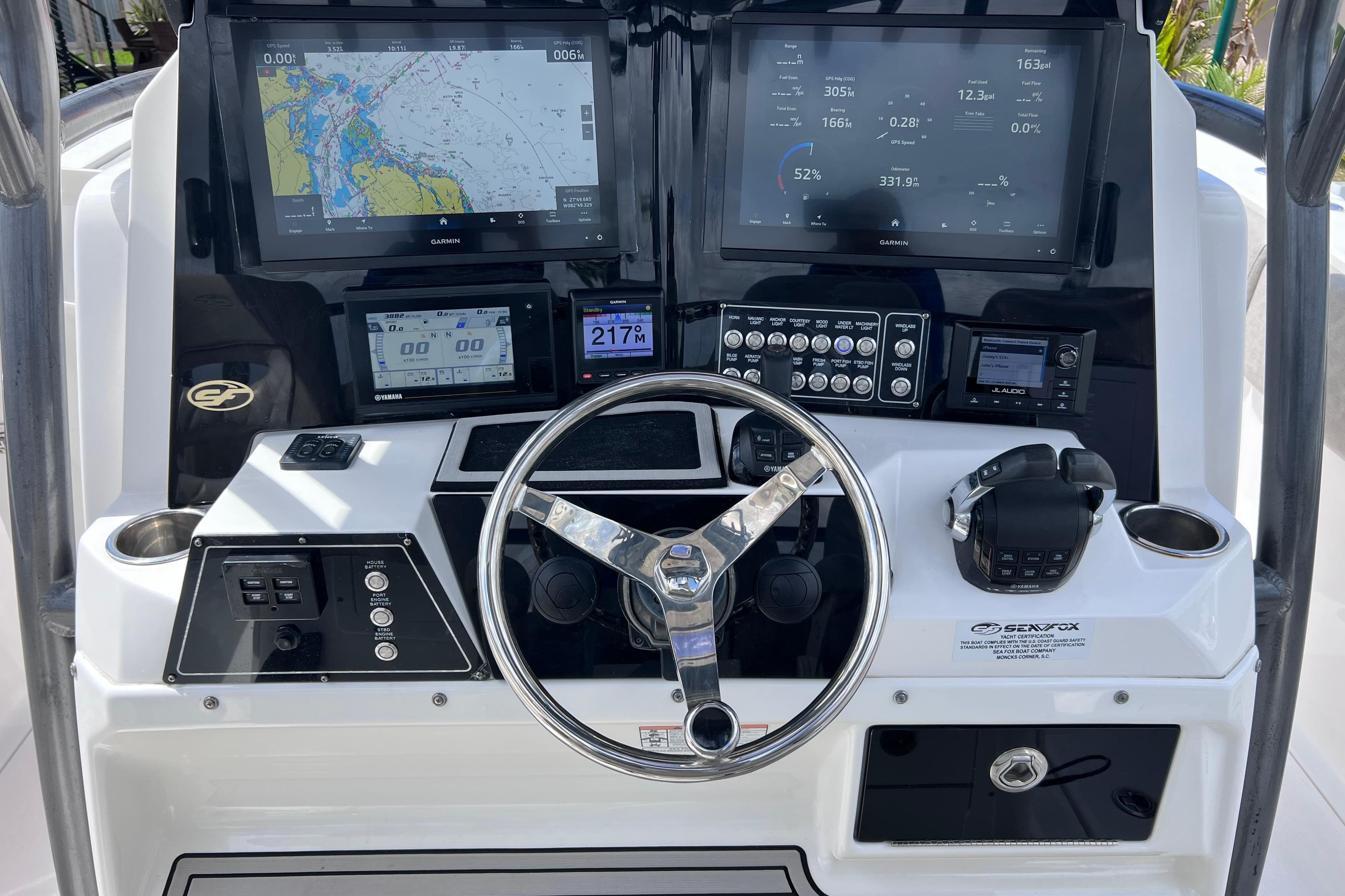Control panel of a 2019 Sea Fox 328 Commander boat with navigation screens and steering wheel.