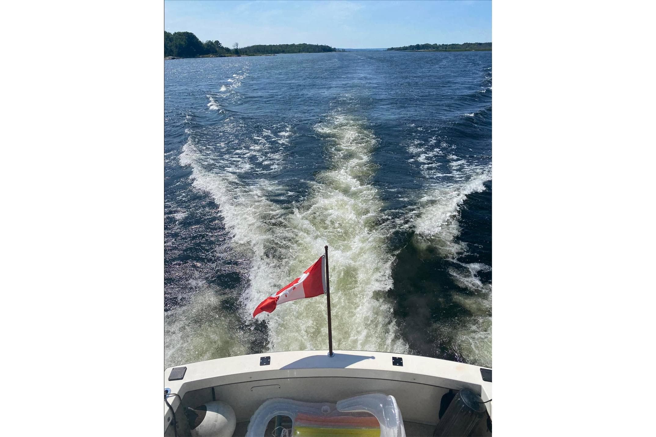 1987 Trojan F-36 Convertible boat cruising with Canadian flag on open water.