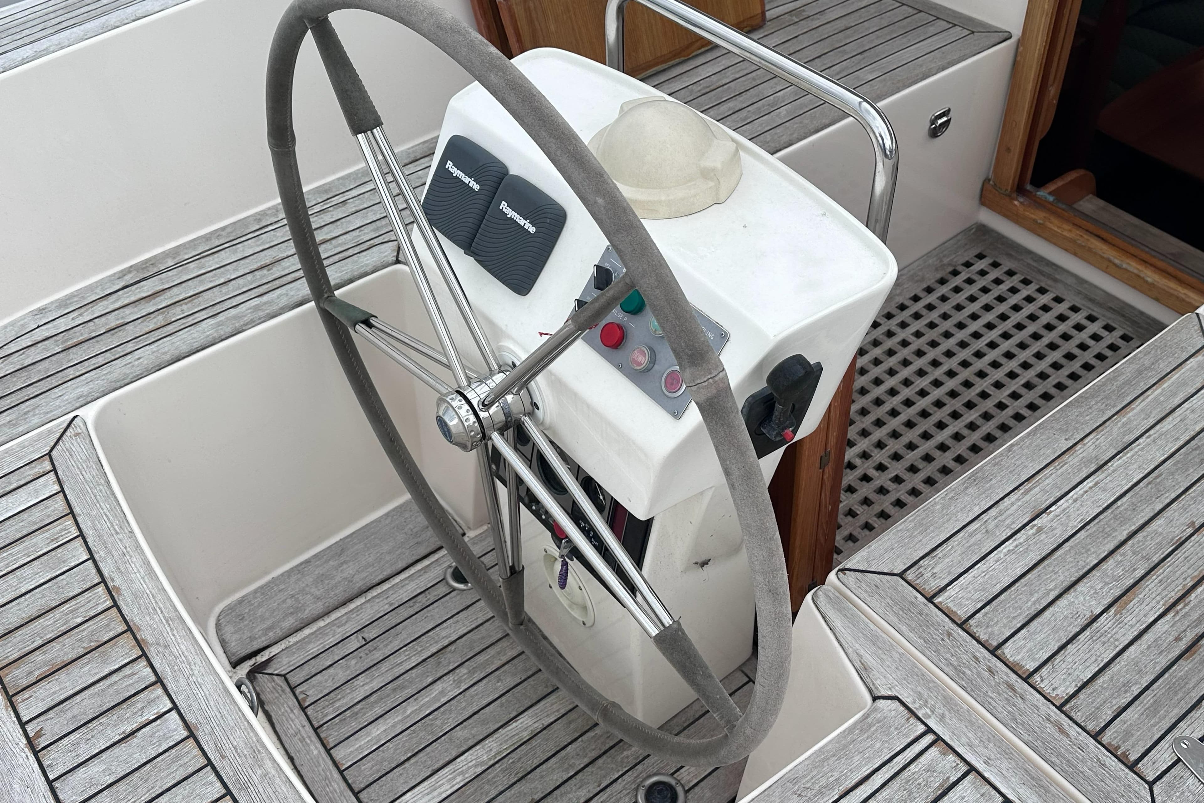 Steering wheel and controls of a 2000 Hallberg-Rassy 46 yacht, featuring teak decking.