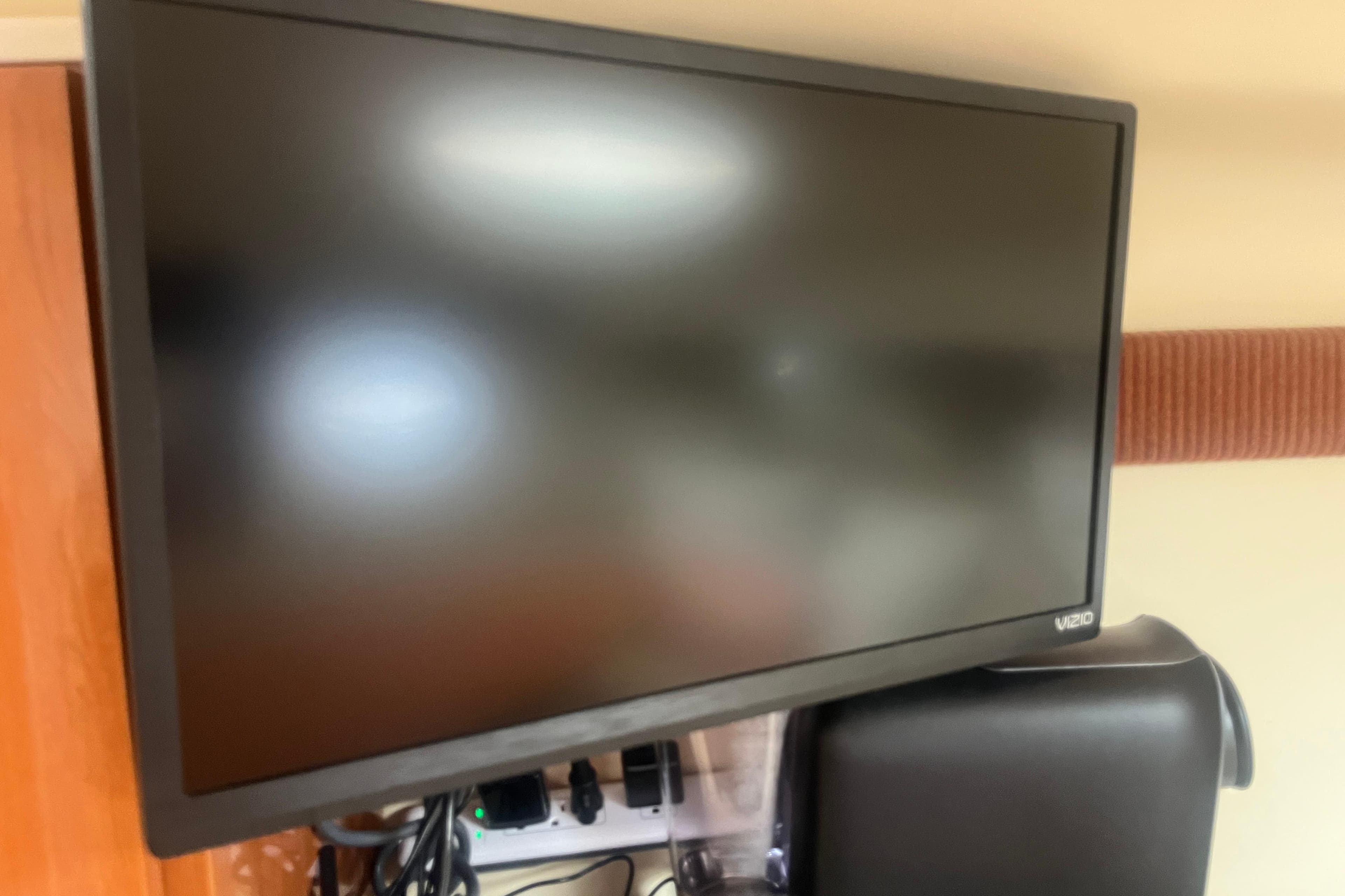 Vizio monitor on a desk with cables and power strip visible.