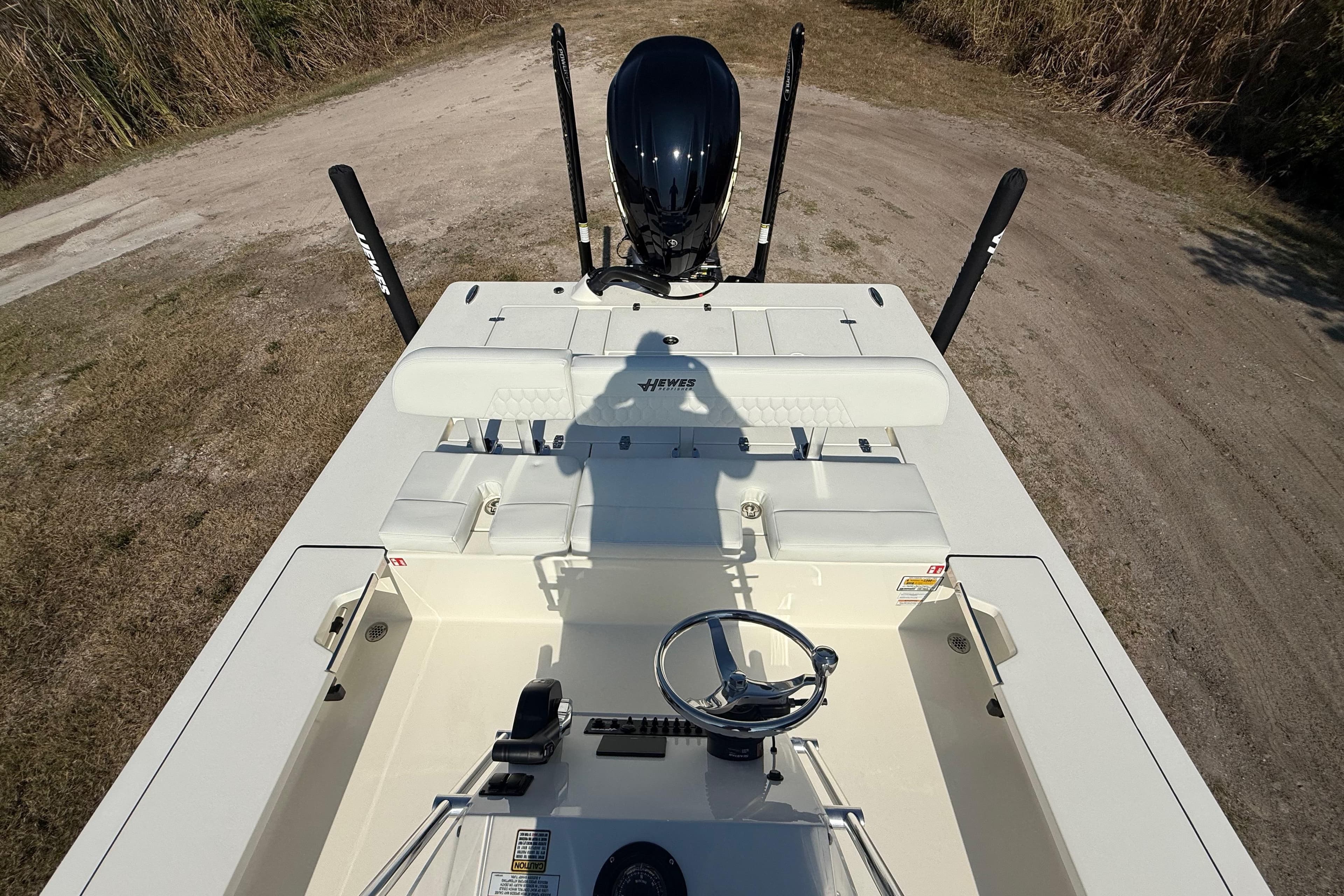 2026 Hewes 21 REDFISHER boat interior with steering wheel and seating, parked on grassy terrain.