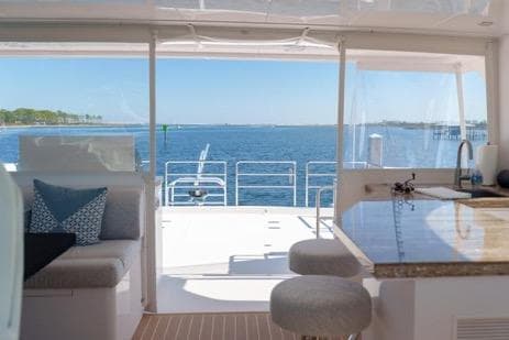 Luxurious Horizon PC65 yacht interior with ocean view, featuring modern seating and kitchen area, 2022 model.