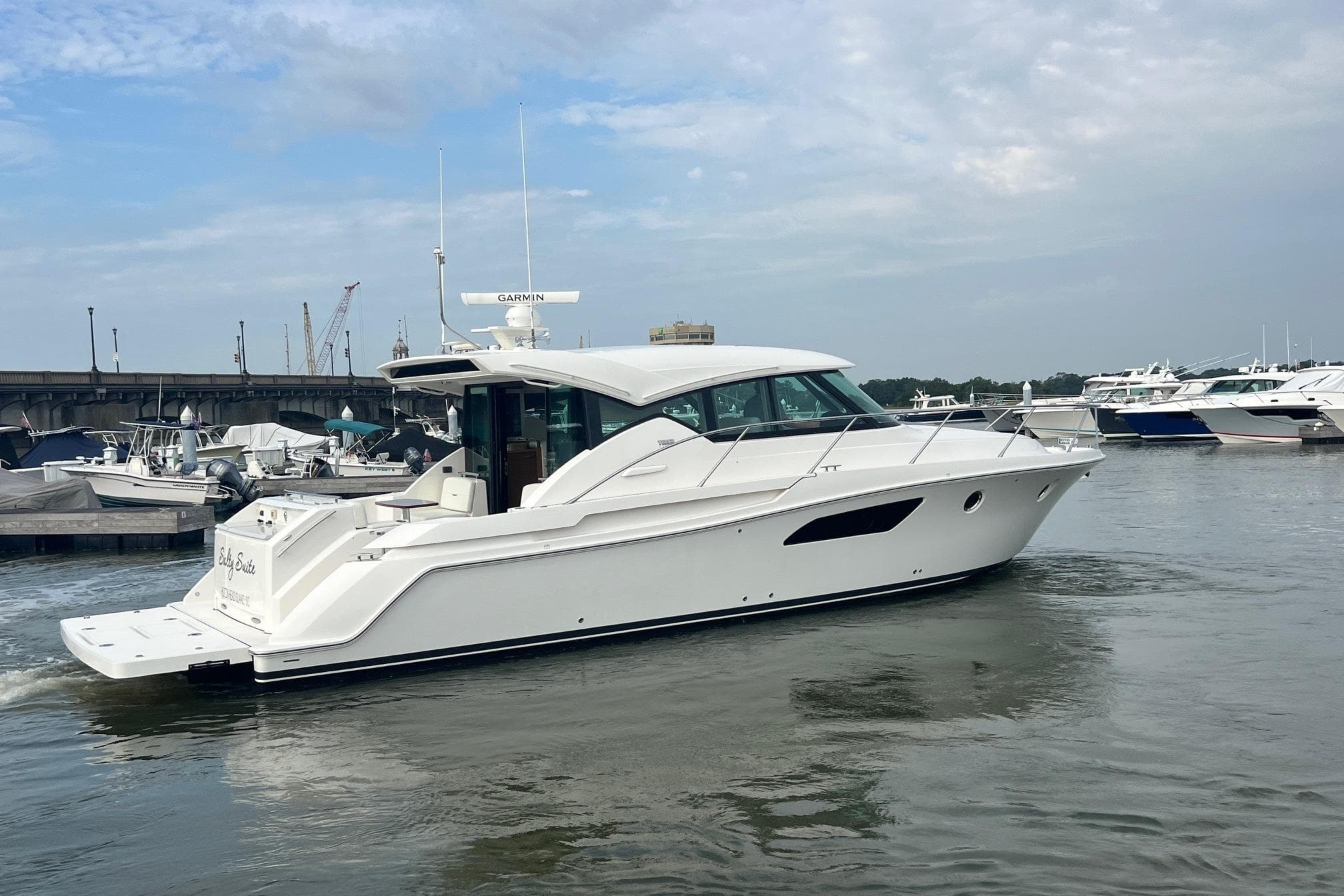 2023 Tiara Yachts C44 Coupe cruising in a marina under a cloudy sky.