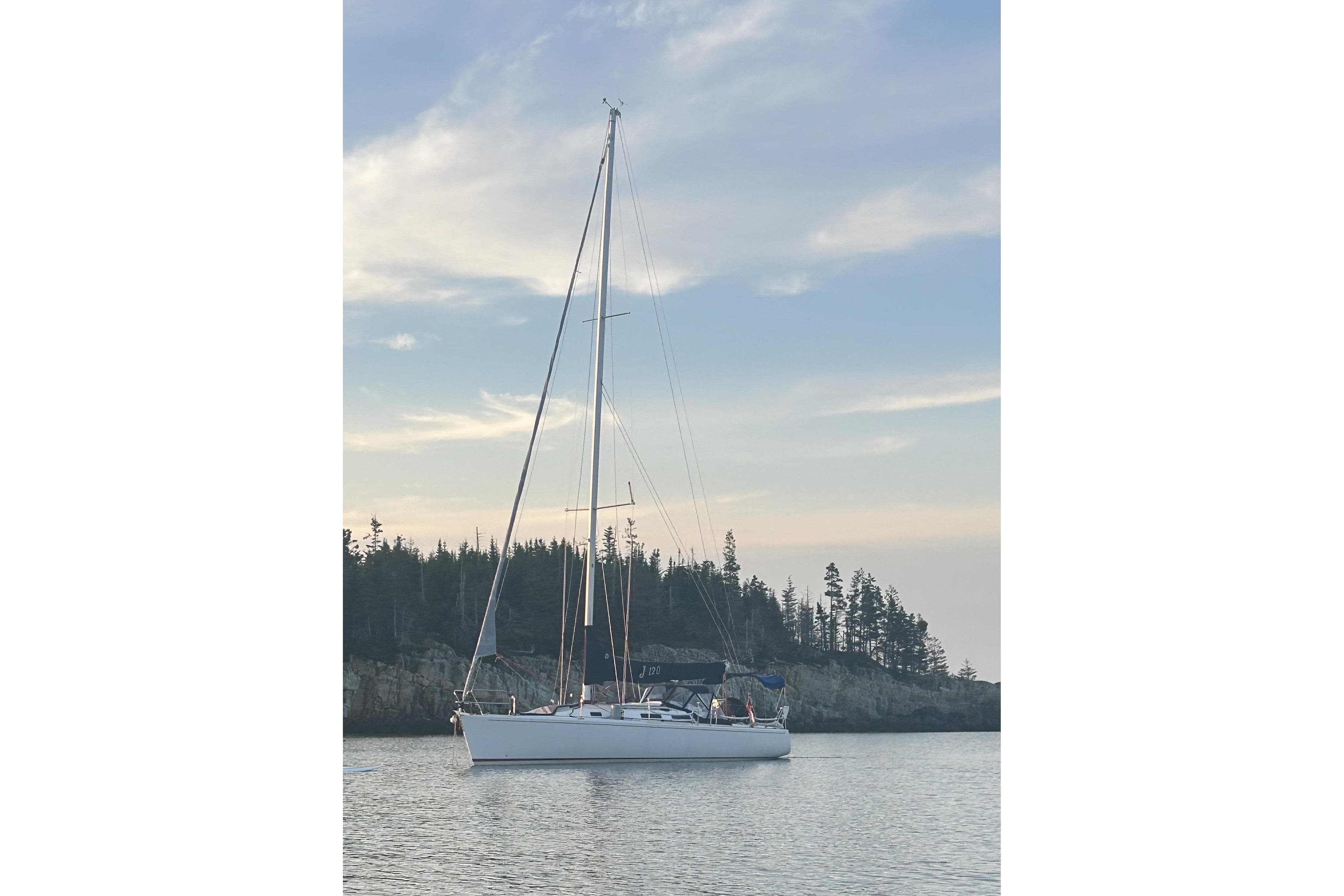 Sailboat J/120 from 2002 by J Boats, anchored near a forested shoreline.