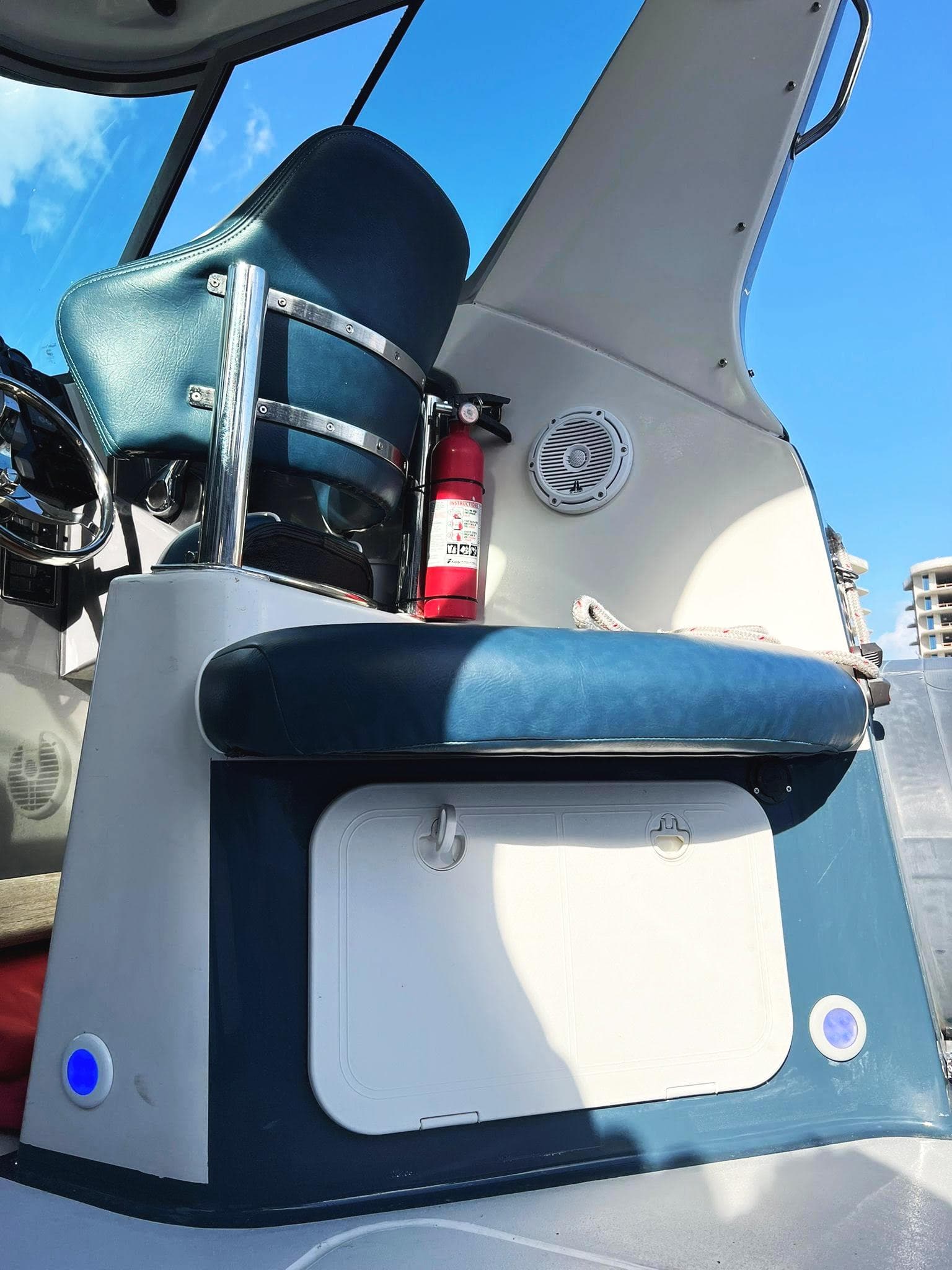 Interior of a 2000 Protector Targa 28 boat with blue seating and fire extinguisher.