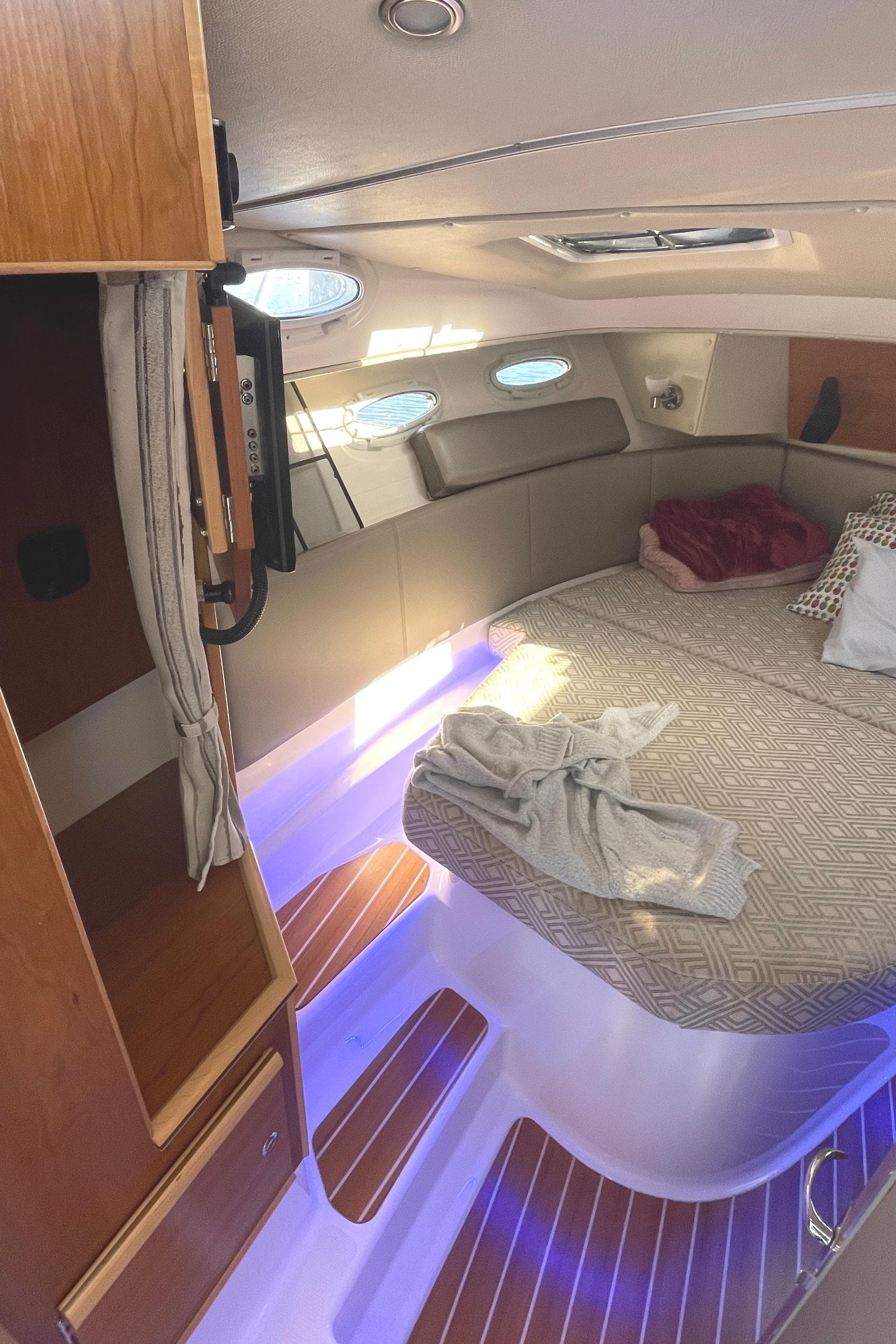 2022 Cutwater Flybridge interior with cozy bed, ambient lighting, and wooden accents.