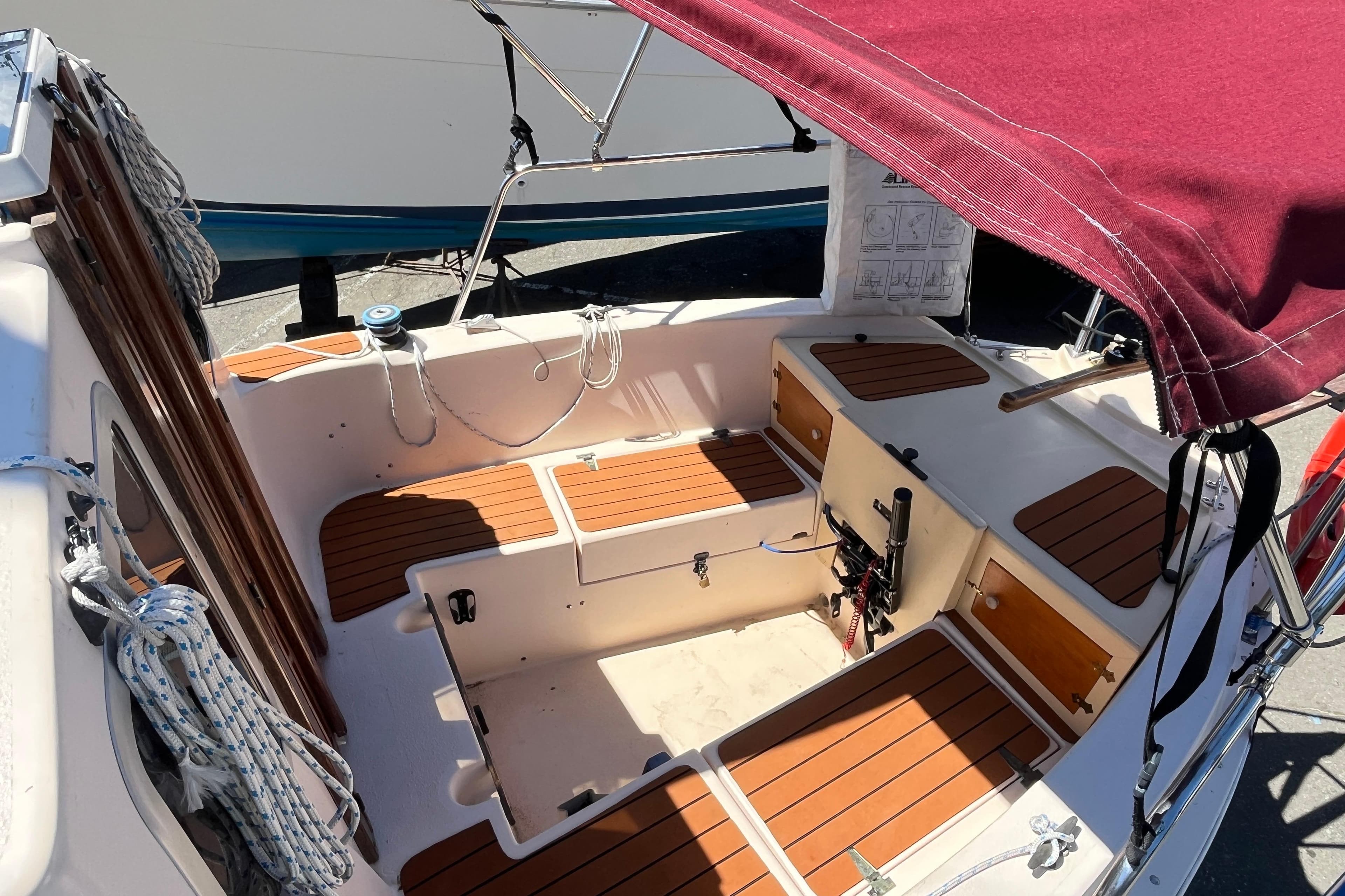 1994 Nimble Kodiak Pilothouse Motor Sailor cockpit with wooden seating and maroon canopy.
