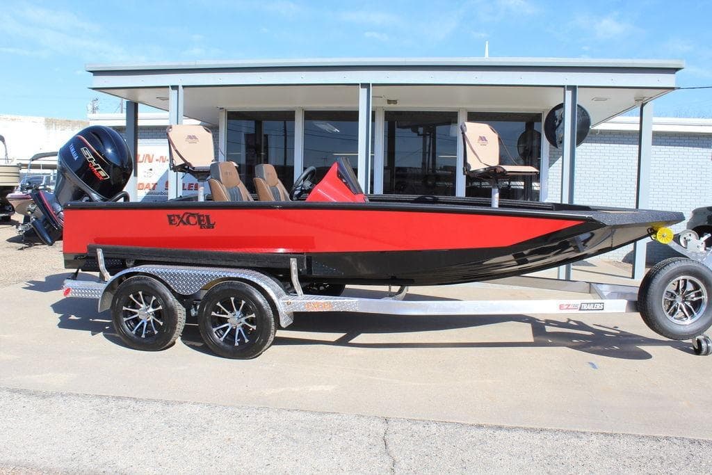 2026 Excel EX 183 boat in red and black on a trailer, parked outside a building.