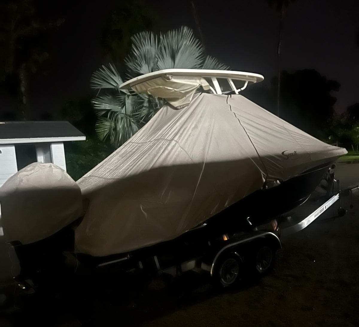 2024 Scout 215 XSF boat covered, parked on trailer at night.