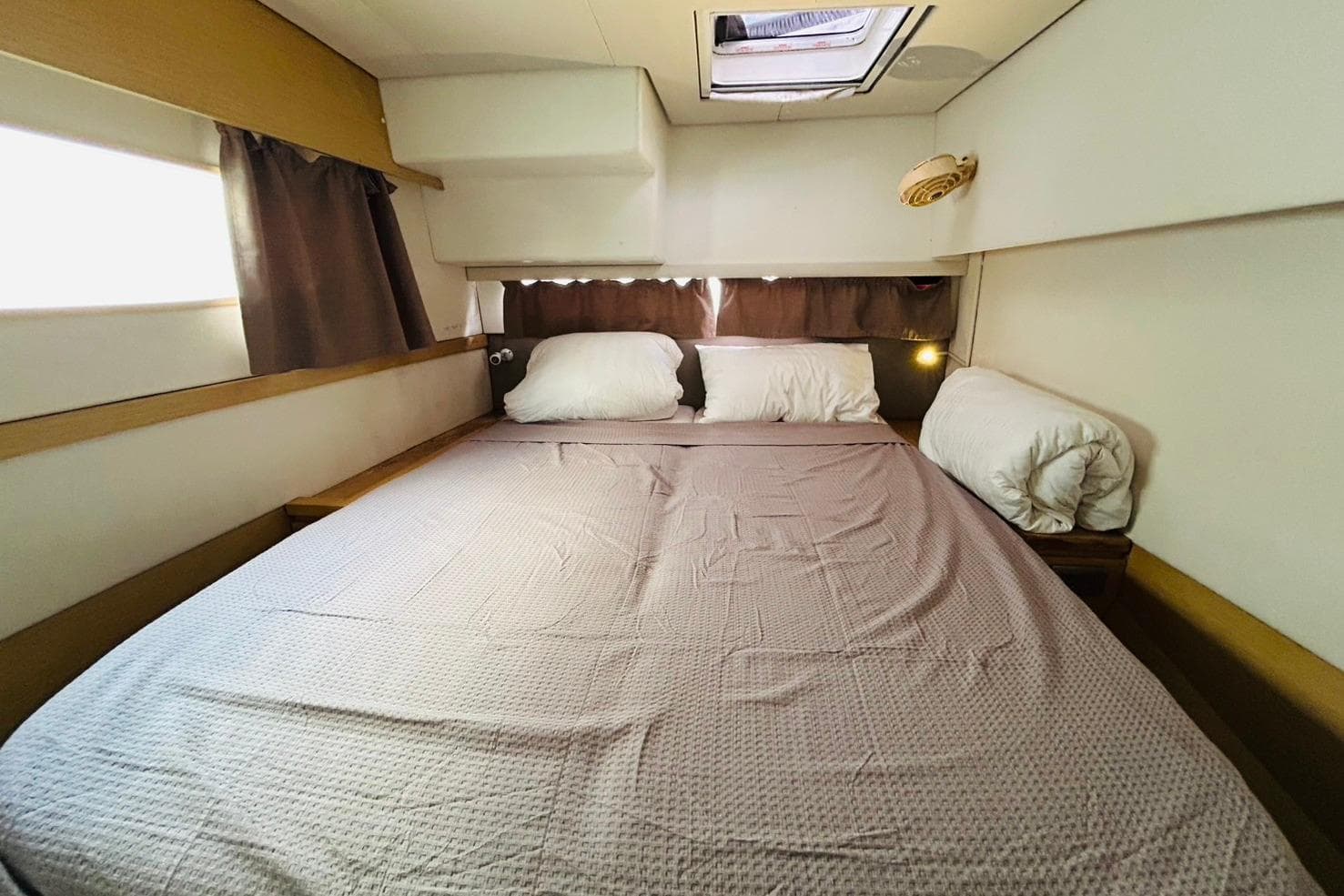Cozy bedroom interior of 2015 Fountaine Pajot SABA50 catamaran with skylight and curtains.